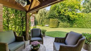 At the end of a dead-end street, you will find this exceptionally well-maintained villa on a beautifully landscaped plot of approximately 2,000 m². The property includes 4 bedrooms, 2-3 bathrooms, and combines a timeless, classic look with comfortable living spaces, plenty of natural light, and a beautiful south-facing garden with optimal privacy.<br /><br />Layout ground floor:<br />We enter the villa through a bright entrance hall with custom-made furniture and a guest toilet. Next, there is a separate office with a built-in library, ideal as a home office, reading room, or discreet workspace.<br /><br />The living room is spacious and pleasantly laid out with a cozy seating area around the fireplace. Large windows provide plenty of natural light and views of the surrounding greenery. Next to the living room, there is a charming garden room/dining area with views of the garden and direct access to the terrace.<br /><br />The kitchen is timelessly designed with light wooden custom-made furniture, plenty of storage space, a central island, and Miele ovens and warming drawer, dishwasher, refrigerator, and freezer. Adjacent to the kitchen, there is a practical storage room with an extra shower and technical space.<br /><br />First floor:<br />Here we find a spacious master bedroom with an adjoining dressing area, equipped with numerous built-in closets. The bathroom is well-appointed with a double sink and bath/shower combination.<br /><br />Also on this floor is an additional room, currently used as a fitness room. This space can be flexibly used as a bedroom, hobby room, or additional office. Additionally, on this floor, there is a separate laundry/ironing room and a separate toilet.<br /><br />Second floor:<br />via the staircase, we reach the 2nd floor. This offers space for 2 spacious bedrooms, both with pleasant natural light, practical storage space, and office possibilities. The landing, equipped with built-in closets, also provides access to the additional shower room with toilet.<br /><br />Garden and outbuildings:<br />The garden has been carefully landscaped and, thanks to its south orientation, enjoys pleasant natural light throughout the day. The terraces seamlessly connect to the living spaces and offer various places to dine or relax outdoors. At the back of the garden, there is a covered lounge area, ideal for long summer evenings in peace.<br /><br />The spacious driveway leads to a separate carport with storage. On the roof of this carport are solar panels, linked to a battery, which contributes to the favorable EPC label B.<br /><br />Particularities:<br />- South-facing, fully landscaped garden with plenty of privacy<br />- Multiple terraces and covered lounge area in the garden<br />- Separate carport with storage<br />- Solar panels with battery<br />- Very favorable EPC label B with a score of 155 kWh/m²/year<br />- Asbestos safe<br />- Electrical inspection, compliant<br />- Within walking distance of St. Ludgardis school, shops, and public transport<br /><br />An exceptionally well-maintained and ready-to-move-in family villa in a prime location where comfort, privacy, and timeless class come together beautifully.