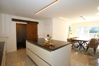 <strong>Uitzonderlijk ruime halfopen bebouwing met 4 slaapkamers, 2 badkamers, volledig onderkelderd en uitbreidingsmogelijkheden op zolderverdiep.<br />Instapklaar!</strong><br /><br />Ruimte, kwaliteit en een ideale ligging komen samen in deze uitzonderlijk ruime halfopen bebouwing van circa 320 m².<br />Achter de verzorgde gevel schuilt een verrassend grote gezinswoning met een doordachte indeling, vier slaapkamers, twee badkamers (waarvan 1 gelijkvloers), een volledige onderkeldering, een zeer ruim zolderverdiep én de mogelijkheid tot omvorming naar twee appartementen.<br /><br />De lichtrijke eetkamer sluit naadloos aan op de volledig uitgeruste keuken met kookeiland. Dankzij de vele maatwerk inbouwkasten is er meer dan voldoende opbergruimte. De woning beschikt over verschillende ruime leefruimtes, vier volwaardige slaapkamers en twee badkamers, waarvan één op het gelijkvloers (hoogwaardig afgewerkt!) en één op de verdieping (kan opfrissing gebruiken).<br /><br />Via een vaste trap bereikt u de zeer ruime zolderverdieping, die dankzij de aanwezige Velux-ramen eenvoudig kan worden ingericht als extra slaapkamers, bureau of hobbyruimte.<br /><br />Het kelderverdiep biedt een koele berging, technische ruimte, een sfeervolle afgewerkte loungeruimte én een uitzonderlijk ruime garage met praktische compartimenten die eveneens makkelijk langs achter te bereiken is met de wagen via een doodlopende weg.<br /><br />Buiten geniet u van een ruim, aangelegd zonneterras met zuidwestelijke oriëntatie, een onderhoudsvriendelijke tuin en een permanent groen uitzicht over open weiland. Dankzij de uitstekende geluidsisolatie ervaart u binnenshuis bovendien een aangenaam wooncomfort, dit ondanks de zeer centrale ligging.<br />De woning werd afgewerkt in 2009 en scoort uitstekend op vlak van energiezuinigheid met een zéér gunstig EPC (label A) en 24 zonnepanelen (met een opbrengst van € 230 per 1.000 kWh. Jaarlijks minimaal 5 groenestroomcertificaten)!<br /><br />Extra troef: de woning is reeds volledig voorbereid op een eventuele opsplitsing naar twee appartementen. De nodige voorzieningen zijn aanwezig, wat mogelijkheden biedt voor kangoeroewonen, een zorgwoning of een investeringsproject (onder voorbehoud van de nodige vergunningen).<br /><br /><strong>Troeven op een rij:<br />+ Recent en moderne woonst<br />+ Uitzonderlijk veel ruimte<br />+ Hoogwaardige afwerking met goede isolatie<br />+ Zeer centrale ligging en toch een uiterst aangenaam wooncomfort<br />+ Energiezuinig! EPC-score - 92 kWh/m² jaar = label A!<br />+ Volledige onderkeldering én zolderverdieping<br /> (in kelder 3-fasige krachtstroomaansluiting (380/400 V) met industriële stekker, geschikt voor professioneel gebruik.)<br />+ Extra mogelijkheden voor kangoeroewonen, zorgwoning of ombouw naar 2 appartement.<br /> Voorzieningen hiervoor zijn reeds aanwezig!</strong><br /><br />