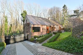 Prachtige, zeer degelijk onderhouden villa gelegen in een idyllisch bebost kader. Dit perceel van 15a73ca is bereikbaar via een rustige wegenis met weinig doorgaand verkeer. Temidden van natuur en bos verschuilt zich deze instapklare villa gebouwd met contouren die de flank van de berg volgen.<br /><br />De villa is volledig onderkelderd, voorzien van gepolierde beton in 2022 en een mooie werkhoogte van 2,65m. De kelder is ingedeeld als dubbele garage, wasplaats en grote berging ruimtes voor het beoefenen van sporten, men cave of als werkruimte.<br /><br />De villa beschikt over een inkomhal met vestiaire ruimte en gastentoilet. Een zeer zonnige woonkamer dankzij de vele raampartijen zuidgericht die een prachtig uitzicht bieden op de groene omkadering. De leefkeuken is uitgerust met alle toestellen en voorziet in veel bergingruimte. Aansluitend een praktische, koele voorraadberging. <br />Er zijn 3 slaapkamers beschikbaar waarvan twee naast de inkomhal die dus perfect mogelijkheden bieden als bureauruimte of praktijk. Een vernieuwde badkamer met inloopdouche. <br />De zolder voorzien van vaste trap biedt  potentieel tot extra slaapkamers. <br /><br />Een instapklare, kwalitatieve villa met een gunstige EPC score B (dak, gevel en vloer isolatie aanwezig, ramen hoogrendement dubbel glas, vernieuwde brander mazout, maar aardgas ligt in de straat als gewenst).  Dubbele waterput. Aangesloten op riolering.<br /><br />De tuin volgt de hellingsgraad van de berg en is volledig omheind en afgesloten via autom toegangspoort. Groot terras met groene omkadering.<br /><br />Wenst u deze villa te bezoeken of meer inlichtingen hierover, contacteer Dupont Vastgoed op 015 15 15 15.<br /><br /> 