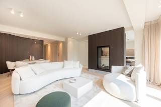 <p>Dit luxueuze appartement, met een oppervlakte van 140 m², ligt op een toplocatie tegenover de Heilig-Hartkerk. Het combineert licht, ruimte en elegantie, perfect voor liefhebbers van comfort.</p>
<p>De gezellige leefruimte straalt warmte en stijl uit, met een uitnodigende zithoek, een aparte eethoek en een verfijnde tunnelhaard die een harmonieuze verbinding vormt met de ruime open keuken. Dankzij de overvloed aan natuurlijke lichtinval en de open indeling ontstaat een modern loftgevoel, terwijl de slaapvertrekken een oase van rust en privacy bieden.</p>
<p>De drie slaapkamers, verbonden door een elegante gang, zijn elk voorzien van een luxueuze ensuite badkamer. Warme, natuurlijke materialen zoals eikenhout en travertin natuursteen creëren een serene en tijdloze sfeer.</p>
<p>Het interieur is tot in de puntjes afgewerkt met maatwerkmeubilair, zorgvuldig gekozen verlichting, verfijnde raamdecoratie en designmeubelen. De eikenhouten parketvloeren in visgraatmotief en de subtiele details versterken de exclusieve uitstraling van het appartement.</p>
<p>Elke ruimte is functioneel en efficiënt ontworpen, met volop opbergruimte en een discrete, ingebouwde wasplaats die via een aparte ingang bereikbaar is. Dit appartement biedt een unieke combinatie van luxe, comfort en doordacht design.</p>
<p></p>