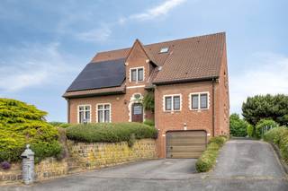 Deze indrukwekkende en perfect onderhouden woning combineert ruimte, comfort en een uitzonderlijke ligging op een prachtig perceel met weids groen uitzicht. Dankzij de royale oppervlaktes, kwalitatieve afwerking en doordachte indeling is dit een ideale gezinswoning met tal van mogelijkheden.<br />Bij het betreden van de woning komt u terecht in een ruime en statige inkomhal met gastentoilet. De lichtrijke woon- en eetkamer beschikt over een royale zithoek rond de sfeervolle open haard, voorzien van een praktische lift naar de kelder waar de houtvoorraad zich bevindt. Aansluitend bevindt zich de volledig vernieuwde keuken met bijkeuken en toegang tot de kelder.<br />Het gelijkvloers beschikt bovendien over een ruime slaapkamer en een badkamer, wat de woning bijzonder geschikt maakt voor gelijkvloers wonen, minder mobiele bewoners of levenslang wonen.<br />De woning is volledig onderkelderd en omvat onder meer een uitzonderlijk ruime inpandige garage met plaats voor vier wagens, een werkruimte, technische ruimte en extra opslagmogelijkheden.<br />Op de eerste verdieping bevinden zich drie zeer ruime slaapkamers. De master bedroom beschikt over twee dressings, waarvan één de oppervlakte heeft van een volwaardige extra slaapkamer. Verder zijn er twee badkamers en een apart toilet aanwezig.<br />Via de ruime nachthal bereikt u de tweede verdieping, die in 2025 werd ingericht en plaats biedt aan nog twee slaapkamers en een vierde badkamer.<br />Ook op vlak van energiezuinigheid scoort deze woning uitstekend dankzij de aanwezigheid van zonnepanelen en een warmtepompboiler. De keuken, badkamers en parketvloeren werden bovendien kwalitatief gerenoveerd, waardoor de woning zich in absolute topconditie bevindt.<br />De achtertuin vormt zonder twijfel één van de grootste troeven van deze eigendom: een gigantisch grasveld met een uniek en rustgevend uitzicht op het omliggende groen.<br />Een uitzonderlijke woning voor wie op zoek is naar ruimte, comfort, kwaliteit en een unieke woonomgeving.<br />Beschikbaar vanaf 01/07/2027.