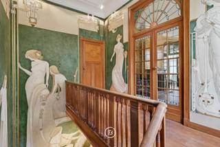 Tussen het Ambiorixplein en de levendige wijk rond Plasky, nabij Diamant en het Jubelpark, bevindt zich dit uitzonderlijke herenhuis met drie gevels, gebouwd in 1912 in verfijnde Beaux-Artsstijl. Met een bewoonbare oppervlakte van circa 631 m² op een perceel van 2a 20ca, biedt deze woning een unieke combinatie van elegantie, ruimte en authenticiteit.<br />Via de hoofdingang aan de prestigieuze Emile Maxlaan betreedt men een wereld van verfijnde architectuur en tijdloze charme. Tal van authentieke elementen werden zorgvuldig bewaard: originele parketvloeren, rijkversierde schouwmantels, fijn lijstwerk, glas-in-looddeuren, siersmeedwerk, fresco’s en ornamenten getuigen van een uitzonderlijk vakmanschap.<br />De prachtige leefruimtes worden gekenmerkt door hoge plafonds, royale volumes en veel natuurlijk licht, wat bijdraagt tot een gevoel van grandeur en harmonie. Deze eigendom leent zich uitstekend tot veelzijdig gebruik – als prestigieuze gezinswoning, kantoorruimte of representatief pand met gemengd karakter.<br /><br />Een pand vol geschiedenis en karakter, dat de grandeur van het begin van de 20e eeuw weerspiegelt en tal van mogelijkheden biedt in één van de meest charmante lanen van Schaarbeek, omgeven door elegante handelszaken, sfeervolle restaurants en uitstekende verbindingen.<br /><br />Indeling<br />Gelijkvloers: majestueuze inkomhal met monumentale trap, verfraaid met een fresco geïnspireerd op het Cauchiehuis, elegante ontvangstruimte met houtwerk en glas-in-loodramen, vestiaire en gastentoilet, volledig uitgeruste keuken met toegang tot terras en tuin, souplex (gelijkvloers + kelder).<br /><br />Eerste verdieping: ruim salon met hoge plafonds en moulures, grote eetkamer met authentieke details, tweede keuken met eetruimte en balkon<br /><br />Tweede verdieping: 3 ruime slaapkamers, dressing, grote badkamer met ligbad, douche en toilet<br /><br />Derde verdieping: 4 slaapkamers<br /><br />Zolderverdieping: volledig geïsoleerd dak vernieuwd in 2025. Mogelijkheid tot inrichting (extra kamers, enz.)<br /><br />Kelderverdieping: ruime kelders, wijnkelder, wasruimte en stookruimte met nieuwe condensatieketel op gas (2022).
