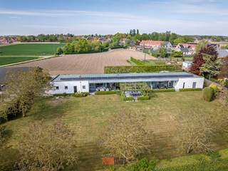 www.egaalstraat26.be<br />In ’95 werd een weldoordacht bouwplan uitgewerkt met licht en ruimte als uitgangspunt. Het resultaat, een eerder modernistische gelijkvloerse villa, te vinden in een bijzonder rustige straat in Kachtem. <br />Opgetrokken op een volledig zuidgericht perceel van 2.600m² in een agrarische omgeving met het pas aangelegde Vageweenbos om de hoek.<br /><br />De focus op de praktische indeling, met het leefgedeelte als ‘center’, maakt het wonen hier bijzonder aangenaam.<br />Quasi de volledige achtergevel bestaat uit hoge raampartijen met centraal een boog die rust en evenwicht creëert. Uniek is het koperen dak, specifiek gekozen om haar duurzaamheid, uitzonderlijke levensduur en weersbestendigheid.<br /><br />Al vanaf de inkomhal voel je je meteen thuis. De geautomatiseerde glazen tussenwand brengt je tot de XL doorloop-woonkamer met annex bureel, super gezellige TV hoek met (doorkijk)haard. Een halve wand scheidt de woonkamer van de praktisch ingerichte keuken met eetplaats, aansluitende berging, dubbele garage, technische berging en toilet.<br /><br />De linkerflank, gezien vanaf de inkomhal, bestaat uit een brede hal met toegang tot de masterbedroom met dressing en recent vernieuwde badkamer met o.a. een XL inloopdouche, Japans toilet, infrarood paneel. <br />De drie overige slaapkamers (14m², makkelijk moduleerbaar) maken gebruik van de tweede badkamer en extra toilet.<br /><br />De super onderhoudsvriendelijke tuin biedt rust en balans. Een strak gazon, serre, heerlijk ontspannen op de zonneterrassen, onder de schaduwrijke notelaars of het centrale terras overdekt met platanen.<br />Mogelijkheid om de aanpalende eigendom (op 4.000m²) eveneens bij te kopen.