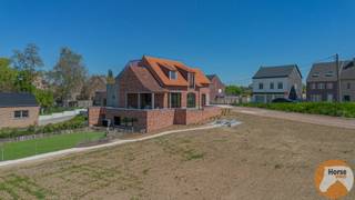 <p><span><strong>LEDE - Exclusieve landelijke woning op unieke ligging</strong><br />EERSTE BEZOEKDAG ZATERDAG 23 MEI VAN 09u TOT 13u (Enkel op afspraak !)<br /></span><br />In het rustige en groene Stichelendries te <span><span>Lede</span></span> bevindt zich deze uitzonderlijke woning van 2025, gelegen op een ruim perceel van maar liefst 5.550 m². Dankzij de open ligging, de prachtige verzichten over het omliggende landschap en de absolute privacy geniet u hier dagelijks van rust, ruimte en natuur in een exclusieve woonomgeving.</p>
<p>Deze stijlvolle villa werd ontworpen in een tijdloze landelijke architectuur en opgetrokken in traditioneel metselwerk met hoogwaardige materialen. De woning combineert authenticiteit en charme met hedendaags wooncomfort en energiezuinige technieken. Bovendien biedt de huidige afwerkingsfase de unieke kans om nog persoonlijke accenten en afwerkingen naar eigen smaak toe te voegen, zodat u deze woning volledig kan afstemmen op uw woonwensen.</p>
<p>Via de royale inkomhal met gastentoilet en elegante traphal wordt u verwelkomd in de bijzonder lichtrijke leefruimte. Grote raampartijen zorgen voor een overvloed aan natuurlijk licht en creëren een prachtig zicht op de omliggende tuin en het achterliggende groen. De gezellige houtkachel vormt het warme hart van de woning en zorgt voor een sfeervolle en uitnodigende leefomgeving. Aansluitend bevindt zich het deels overdekte terras, waar u in alle rust kan genieten van lange zomeravonden en het weidse uitzicht.</p>
<p>De leefruimte staat in directe verbinding met de bureauruimte, ideaal voor thuiswerk of een praktijk aan huis, en met de ruime open keuken. Deze keuken biedt tal van mogelijkheden voor een stijlvolle inrichting en wordt aangevuld met een praktische berging/wasruimte die extra comfort en opbergruimte voorziet.</p>
<p>Op de eerste verdieping bevindt zich de ruime master bedroom met aansluitende dressing, een tweede volwaardige slaapkamer en een royale badkamer uitgerust met ligbad en de mogelijkheid tot het installeren van een douche. Verder vindt u hier nog een apart toilet en een extra berging. De polyvalente leefkelder biedt bijkomende mogelijkheden en kan perfect ingericht worden als derde slaapkamer, hobbyruimte, fitness, speelkamer of extra bureau.</p>
<p>Ook technisch voldoet deze woning aan de hedendaagse normen inzake comfort en energiezuinigheid. Zo werd de woning uitgerust met vloerverwarming, een energiezuinige warmtepomp lucht/lucht, ventilatiesysteem D, aluminium/houten ramen met hoogrendementsglas en een regenwaterput van 10.000 liter. Het EPB Nieuwbouwattest is momenteel in opmaak.</p>
<p>Buiten werd de tuin recent ingezaaid en geniet u van een prachtig groen kader rondom de woning. Daarnaast is er reeds een tuinberging aanwezig en bestaat de mogelijkheid om een carport te voorzien. Voor de verdere afwerking zijn bovendien reeds kwalitatieve materialen aanwezig, waaronder stijlvolle eiken binnendeuren en blauwe steen terrastegels.</p>
<p>Bent u op zoek naar een exclusieve woning met karakter, ruimte en een unieke ligging in het groen? Aarzel dan niet om ons te contacteren op 053/60.65.66 voor meer informatie of een bezoek ter plaatse en ontdek zelf de charme en mogelijkheden van deze uitzonderlijke eigendom.<br />De prijs is een niet-bindende richtprijs. Na biedingen beslist de verkoper over verkoop aan het beste bod. Info via ons of reglement.</p>