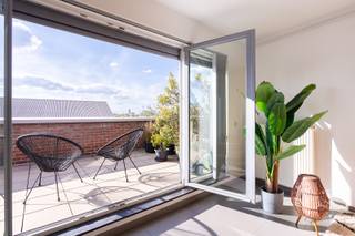 Lichtrijk duplex penthouse met uitzonderlijk terras<br /><br />Locatie<br />Op een gegeerde locatie op 'den Dam' bevindt zich dit exclusieve duplexpenthouse op wandelafstand van het Eilandje en Park Spoor Noord, de groene long aan de rand van de Stad. Ook winkels, restaurants, openbaar vervoer en belangrijke invalswegen zijn vlot bereikbaar. De Mobiscore van 9,5/10 is dan ook het logische gevolg.<br /><br />Beschrijving<br />Het duplex penthouse maakt deel uit van een verzorgd gebouw en is bereikbaar met de lift. Dankzij de hoge ligging geniet u van veel privacy, een uitstekende lichtinval en indrukwekkende vergezichten over Antwerpen. De benedenverdieping van de duplex omvat een royale leefruimte met grote raampartijen aan meerdere zijden. Hierdoor baadt het interieur de hele dag in het natuurlijke licht. De woonkamer sluit naadloos aan op de eetplaats en de ruime, uitgeruste keuken. Deze werd kwalitatief afgewerkt en beschikt over diverse ingebouwde toestellen. Rondom de leefruimtes strekt zich een uitzonderlijk driezijdig terras uit. De verschillende oriëntaties zorgen ervoor dat u op meerdere momenten van de dag van de zon kunt genieten, steeds met een weids uitzicht over de stad. Op de bovenverdieping bevinden zich twee slaapkamers met veel lichtinval en praktische maatkasten. De eigentijdse badkamer is ingericht met een inloopdouche. Zowel op de onderste als op de bovenste verdieping is bovendien een afzonderlijk toilet aanwezig. Bewoonbare opp. volgens EPC: 118m².<br /><br />Bijzonderheden<br />- Energiezuinig<br />- Conforme elektrische keuring<br />- Maandelijkse lasten werkkapitaal: 240 euro (incl.: professionele syndicus, blokpolis, poetsdienst gemeenschappelijke delen, elektriciteit gemeenschappelijke delen en onderhoud van de lift)<br />- Aparte meters voor water, gas en elektriciteit<br />- Ondergrondse garagebox en kelderberging optioneel aan te kopen<br /><br />Verplichte vermeldingen<br />EPC: 119 kWh/m²<br />P-score: D<br />G-score: D<br />Stedenbouwkundige inlichtingen: Vg, Wg, Vkr, Gmo, Gvv