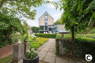 <p><span>Exclusieve architectenwoning met binnen/buitenzwembad op toplocatie in Mortsel</span></p><p><span> </span></p><p><span>Deze uitzonderlijke architectenwoning, gelegen in een gegeerde residentiële wijk nabij het Park van Mortsel, combineert tijdloze architectuur met design, functionaliteit en een uitzonderlijk wooncomfort. Een unieke eigendom voor wie op zoek is naar ruimte, licht, privacy en karakter.</span></p><p><span>De ligging vormt een absolute meerwaarde: rustig en groen, terwijl scholen, winkels, openbaar vervoer en tal van ontspanningsmogelijkheden zich op wandelafstand bevinden.</span></p><p><span> </span></p><p><span>Een bekroond architecturaal concept</span></p><p><span>Deze bijzondere woning werd ontworpen door architect Lou Jansen, die voor dit ontwerp de tweede prijs van de Robert Maskens-prijs (1980) ontving. De realisatie is het resultaat van een succesvolle samenwerking met interieurarchitect Adri Hazebroek, waarbij architectuur en interieur naadloos in elkaar overvloeien.</span></p><p><span>De woning werd in de lengte gebouwd en harmonieus geïntegreerd in de prachtig aangelegde tuin, die zich uitstrekt over twee percelen met een totale oppervlakte van ongeveer 950 m².</span></p><p><span>De solide metalen draagstructuur met een welbepaald ritme van voor- tot achteraan de woning bepaalt de verschillende leefruimtes. Zowel de individuele ruimtes als de gemeenschappelijke zones vormen samen één visueel doorlopend geheel, waarbij licht, ruimte en groen centraal staan.</span></p><p><span> </span></p><p><span>Indeling</span></p><p><span>Gelijkvloers </span><span> </span></p><p><span> </span></p><p><span>De volledig uitgeruste leefkeuken vormt zonder twijfel het hart van de woning. Vanuit de keuken geniet u van een directe toegang tot het terras en de tuin, terwijl het open ontwerp voortdurend contact houdt met de verschillende leefruimtes.</span></p><p><span>De keuken werd tot in de kleinste details doordacht. Hoogwaardige materialen en kwalitatieve toestellen zorgen voor optimaal gebruiksgemak, waaronder een inductiekookplaat, vaatwasser, oven, warmhoudlade, microgolfoven, dubbele spoelbak, ingebouwde friteuse en een duurzaam werkblad in roestvrij staal. Zelfs praktische details, zoals een discreet geïntegreerd opstapje voor de hoge kasten, werden zorgvuldig uitgewerkt.</span></p><p><span>Aansluitend bevindt zich een praktische hal met vestiaire, die rechtstreeks toegang geeft tot de wasplaats, de dubbele inpandige garage en de inkomhal. Ook de ruime kelder is vanuit de keuken gemakkelijk bereikbaar.</span></p><p><span>De kelderverdieping biedt bijzonder veel bergruimte en huisvest alle technische installaties van de woning. Daarnaast beschikt de woning over een sfeervolle, professioneel ingerichte wijnkelder waar uw wijncollectie onder ideale omstandigheden kan worden bewaard.</span></p><p><span> </span></p><p><span>Leefniveau</span></p><p><span>Via een korte trap bereikt u het centrale leefniveau, waar de architecturale kwaliteiten van deze woning volledig tot hun recht komen. De leefruimtes openen zich naar de tuin en genieten dankzij de grote glaspartijen van een overvloed aan natuurlijk licht.</span></p><p><span>De lichtrijke eetkamer vormt het centrale punt van deze verdieping en wordt langs de zijkant volledig omringd door groen. Aansluitend bevindt zich een eerste elegant salon met een prachtig zicht op de aangelegde tuin, de terrassen en het zwembad. Deze ruimte is ideaal om gasten te ontvangen of in alle rust te genieten van een aperitief, terwijl de groene omgeving een unieke, zuiderse sfeer creëert.</span></p><p><span>Verder op het leefniveau bevindt zich een tweede, meer intieme zithoek met een gezellige open haard. Deze tv- en familieruimte sluit naadloos aan op de bureauruimte, die jarenlang dienstdeed als bureau- en ontvangstruimte. Vandaag biedt deze veelzijdige ruimte tal van mogelijkheden als thuiskantoor, speelruimte of extra leefruimte. Dankzij de afsluitbare indeling geniet u hier van een perfecte balans tussen verbondenheid en privacy.</span></p><p><span> </span></p><p><span>Nachtniveau</span></p><p><span>De masterbedroom bevindt zich op een afzonderlijk niveau van de woning en vormt een volledig private suite.</span></p><p><span>Deze ruime slaapkamer beschikt over een praktische dressing en een luxueuze en-suite badkamer, uitgerust met een bubbelbad, een ruime inloopdouche en een stijlvol lavabomeubel.</span></p><p><span>Aansluitend bevindt zich een gezellig privéterras waar u in alle rust kunt genieten van een koffie in de ochtend of een ontspannen avond met zicht op het omliggende groen.</span></p><p><span>Vanuit dit niveau heeft u bovendien toegang tot de wellnessruimte met sauna, fitnessruimte en het verwarmde binnenzwembad dat naadloos overloopt in het buitenzwembad.</span></p><p><span> </span></p><p><span>Bovenste verdieping</span></p><p><span>Op de bovenste verdieping bevinden zich twee volwaardige slaapkamers, een aparte gastenkamer en een tweede badkamer.</span></p><p><span>De tweede badkamer is praktisch ingericht met een douche en een stijlvol lavabomeubel en vormt een aangename meerwaarde voor de slaapkamers en eventuele gasten.</span></p><p><span>De gastenkamer beschikt over een extra zitruimte in de nok van de woning. Dankzij de bijzondere lichtinval is dit een ideale plek om rustig te lezen, te ontspannen of te genieten van een moment voor uzelf. De architecturale vormgeving van de nok zorgt hier voor een bijzonder sfeervolle ruimte met karakter.</span></p><p><span> </span></p><p><span>Buitenleven</span></p><p><span>ook buiten werd niets aan het toeval overgelaten.</span></p><p><span>de fraai aangelegde tuin beschikt over meerdere zonneterrassen, een verwarmd binnen- en buitenzwembad en een prachtige groene pergola achteraan het perceel, waardoor u zich meteen in zuid-frankrijk waant.</span></p><p><span>een ruime tuinberging biedt voldoende plaats voor al het tuinmateriaal. de tuin werd bovendien bijzonder verzorgd aangelegd en is dankzij de doordachte inrichting aangenaam te onderhouden.</span></p><p><span>een extra troef is het tweede perceel achteraan de woning, dat bereikbaar is via zowel de lusthovenlaan als de vernieuwde Edmond Thieffrylaan. het achterste gedeelte van het perceel ligt bovendien op bouwgrond, wat extra potentieel biedt.</span></p><p><span> </span></p><p><span>Comfort en technieken</span></p><p><span>doorheen de jaren werd de woning voortdurend gemoderniseerd met bijzondere aandacht voor kwaliteit, duurzaamheid en energiezuinigheid. dit resulteert in een gunstig EPC-label b.</span></p><p><span> </span></p><p><span>De woning beschikt onder meer over:</span></p><p><span>·Zonnepanelen</span></p><p><span>·Vloerverwarming</span></p><p><span>·Airconditioning</span></p><p><span>·Luchtverwarming gestuurd door een recente gasketel</span></p><p><span>·Gedeeltelijk zonwerend glas</span></p><p><span>·Glass Heating-beglazing op geselecteerde ramen</span></p><p><span>·Verwarmd binnen- en buitenzwembad met warmtepomp</span></p><p><span>·Dubbele inpandige garage</span></p><p><span>·Ruime kelder en wijnkelder</span></p><p><span> </span></p><p><span>Een unieke woonbeleving</span></p><p><span>Deze uitzonderlijke architectenwoning combineert bekroonde architectuur met hedendaags comfort, hoogwaardige afwerking en een unieke beleving van binnen- en buitenruimte.</span></p><p><span>Een zeldzame opportuniteit voor wie op zoek is naar een exclusieve woning op een toplocatie in Mortsel, waar kwaliteit, ruimte, natuur en luxe perfect samenkomen.</span></p><p><span>Deze woning moet u voelen en beleven. </span></p><p><span>Maak een afspraak op www.coprimmo.be of 03/449.49.77</span></p><p><span> </span></p><p><span> </span></p>