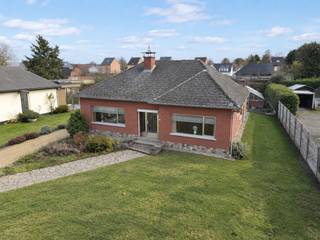 Rustig wonen in het landelijke Sint-Adriaan, Haacht, vlak bij de Dijle en omringd door wandel- en fietsroutes! Deze vrijstaande laagbouwwoning (1971) staat op een breed perceel met zuidwestgerichte achtertuin, waardoor je van ’s middags tot ’s avonds van de zon kan genieten.<br /><br />Alles bevindt zich op het gelijkvloers: een lichtrijke woonkamer met houtkachel, keuken met toegang tot veranda, ruime inkomhal met vestiairekast, 2 slaapkamers, badkamer (ligbad, lavabo, bidet) en apart toilet.<br /><br />Extra troeven: inpandige garage met automatische sectionale poort, een bergzolder, apart garagegebouw, glazen serre en tuinberging.<br />EPC-score 574 (label F - onderhevig aan renovatieverplichting)<br /><br /><br />INDELING<br /><br />Gelijkvloers: inkomhal (vestiairekast, installatie elektriciteit), woonkamer (houtkachel, schouw), keuken (dubbele spoelbak, dampkap, aanbouwkasten), veranda, slaapkamer 1 (watermeter), afzonderlijk toilet, badkamer (lavabo, ligbad, bidet), slaapkamer 2, stookplaats (aansluiting wasmachine, verwarmingsketel), inpandige garage (1 wagen, met automatische sectionaalpoort).<br /><br />Verdieping: bergzolder<br /><br />Exterieur: apart garagegebouw (1 wagen, met kantelpoort), tuinberging, glazen serre.<br /><br /><br />DIVERSEN<br />Ramen in aluminium met deels dubbele beglazing. Centrale verwarming op stookolie met radiatoren - condenserende stookolieketel geplaatst in 2018 - ondergrondse stookolietank van 5000 L. Pvc rolluiken met elektrische besturing en met lint. <br />Regenwatertank: 1 000 L. <br /><br /><br />STEDENBOUWKUNDIG :<br />Stedenbouwkundige vergunning : ja<br />Stedenbouwkundige bestemming : woongebied<br />Geen rechterlijke herstelmaatregel of bestuurlijke maatregel opgelegd.<br />Voorkooprecht : nee | Verkavelingsvergunning : ja<br />Opgenomen in inventaris leegstaande gebouwen.<br />P-score : A / G-score : A