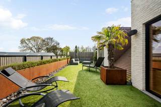 Dit exclusieve appartement spreidt zich uit over twee verdiepingen en biedt comfort, ruimte en luxe op hoog niveau. Op de eerste verdieping treft u een ruime en lichtrijke leefruimte met aansluitend een gezellig terras. Daarnaast omvat deze verdieping een volledig ingerichte leefkeuken met praktische berging, een masterbedroom met ensuite luxebadkamer en dressing, evenals een aparte wasplaats. De tweede verdieping beschikt over twee volwaardige slaapkamers, een sfeervolle zithoek, een kitchenette en een wellnessbadkamer met sauna.<br />In de kelderverdieping zijn een afgesloten garagebox met twee ruime staanplaatsen en een private berging aanwezig.<br /><br />Topklasse afwerking gegarandeerd!<br /><br />Indeling<br />Het appartement is toegankelijk via zowel een vaste trap als een lift die rechtstreeks uitkomt in het appartement. In de inkomhal, voorzien van een gastentoilet, krijgt u toegang tot enerzijds de eetkamer met open keuken en anderzijds de gezellige zitruimte. In de zitruimte komt u volledig tot rust dankzij de sfeervolle dubbelwandige gashaard. De eetkamer sluit naadloos aan op de prachtig uitgeruste keuken, die voorzien is van hoogwaardige toestellen zoals een oven, steamer, ingebouwd koffiezetapparaat, inductiekookplaat, afzuigkap, koelkast, vaatwasser en een Quooker-kraan. Aansluitend vindt u een praktische berging.<br />Ook de masterbedroom met ensuite badkamer en dressing is op deze verdieping terug te vinden. Via het grote schuifraam in de eetkamer heeft u toegang tot het eerste terras, uitgerust met een premium terrasoverkapping, screens en infraroodverwarming.<br /><br />De tweede verdieping, eveneens bereikbaar met de lift, omvat een polyvalente ruimte die momenteel is ingericht als gezellige zithoek met gashaard. Verder zijn hier een kitchenette, twee slaapkamers en een badkamer met sauna voorzien. Vanuit de badkamer heeft u rechtstreeks toegang tot het tweede terras met jacuzzi.<br /><br />In de kelderverdieping beschikt het appartement over een afgesloten garagebox met twee ruime staanplaatsen en een praktische berging.<br /><br />Achteraan het gebouw ligt een prachtig aangelegde gemeenschappelijke tuin, waar u na een drukke dag heerlijk kunt ontspannen.<br /><br />Bijzonderheden:<br />* Airconditioning<br />* CV-installatie op aardgas met vloerverwarming<br />* Prachtige gemeenschappelijke tuin<br />* Rustige en groene ligging<br />* Twee ruime terrassen (zuidoost georiënteerd)<br />* Ventilatiesysteem<br />* Allround geluidsinstallatie<br />* Zonnepanelen