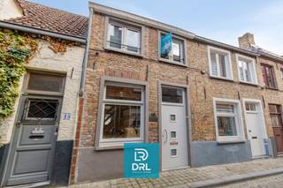 Deze charmante stadswoning is ideaal gelegen in het rustige gezellekwartier van de Brugse binnenstad, vlakbij Sint-Annakerk. Ze combineert comfort met een uiterst centrale ligging. Dankzij grote raampartijen en lichtkoepels geniet de woning van een aangename lichtinval de ganse dag door. In de inkomhal is een kelderfietsberging (spinde) en een gastentoilet. De aangename leefruimte, met grote keuken biedt uitzicht op het gezellige tuintje en geeft via een trapje toegang tot de 'voute' waar een smaakvol bureel is ingericht. Op de eerste verdieping is er een ruime slaapkamer en een 'slaapnis'. De 2e kleine slaapkamer bevindt zich tussen de slaapkamer en de slaapnis. De badkamer bevindt zich op de gelijkvloerse verdieping. Het aangename, zonnige stadstuintje is voorzien van een tuinhuis/berging. Er is een garagepark in de onmiddellijke omgeving waar regelmatig garages te huur komen. Kortom een de geschikte woning voor wie rustig wil wonen met alle stadsvoorzieningen binnen handbereik. <br />Meer info of een bezoek inplannen? Contacteer DRL VASTGOED, info@drlvastgoed.be, 050 65 95 95