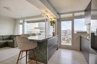 Op de 9de verdieping van een verzorgd residentieel gebouw bevindt zich dit gerenoveerde appartement (105 m² BVO) waar licht, ruimte en comfort centraal staan. Dankzij de hoge ligging geniet u hier elke dag van een indrukwekkend panoramisch uitzicht over de Gentse skyline, terwijl de dubbele terrasoriëntatie zorgt voor zon op elk moment van de dag.<br /><br />De leefruimte baadt in het licht en sluit naadloos aan op de stijlvolle open keuken, die in 2026 volledig werd vernieuwd met hoogwaardige materialen en een eigentijdse afwerking. Het appartement beschikt verder over twee volwaardige slaapkamers, een comfortabele badkamer, een afzonderlijk toilet en een praktische keukenberging. Verder is er nog een privatieve kelderberging.<br /><br />Met terrassen aan beide zijden van het appartement (samen goed voor ca. 15 m²) geniet u zowel van de ochtend- als avondzon en haalt u het buitengevoel volledig naar binnen.<br /><br />Ook op technisch vlak scoort deze eigendom bijzonder sterk. Met een EPC-score van slechts 106 kWh/m²jaar (label B), een energiezuinige warmtepomp, conforme elektriciteit en een asbestveilig attest bent u verzekerd van een toekomstgerichte woonst zonder zorgen.<br /><br />Het appartement is centraal gelegen aan de Martelaarslaan, tussen Gent-Sint-Pieters en het historische stadscentrum. Winkels, horeca, openbaar vervoer en belangrijke invalswegen bevinden zich vlakbij, terwijl u op de 9de verdieping geniet van rust, licht en een uniek uitzicht over de stad.<br /><br /><br /><br />Bestuursmaatregelen in het maatregelenregister: nee