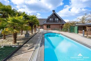 <p>This timeless villa is located in a quiet cul-de-sac near the Dender, just outside the village center of Wieze – a charming town located between Aalst and Dendermonde.<br />Peace and privacy are guaranteed thanks to the favorable positioning of the home and the enclosed rear garden. The property sits on a plot of 2,200 m², with a living area of over 300 m².<br />The ground floor offers a spacious entrance hall with guest toilet and cloakroom area, a home office, a cosy living room with fireplace and dining area, a fully equipped kitchen and an integrated double garage.<br />On the first floor, there are five spacious bedrooms, including two with a balcony and one with a private dressing room. The property has two bathrooms: one with a shower, and one with both a shower and a bathtub. One of the bathrooms is accessible from both the hallway and directly from a bedroom.<br />The beautifully landscaped sun terrace with palm trees, the pool house with heated swimming pool, and the garden shed of no less than 80 m² invite you to relax in total privacy.<br />The property is energy-efficient (EPC A – 84 kWh/m²), asbestos-safe, and has a compliant electrical installation.<br />This villa is in immaculate condition and offers endless possibilities. Perfect as a family home for a large household, or even as a multigenerational (kangaroo) home.<br />In short, a rare opportunity for anyone looking for a stylish, high-quality and move-in-ready villa in a peaceful, green setting.</p>