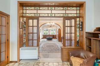 Deze interbellumwoning uit 1938 is een unieke combinatie van authentieke uitstraling, een groene omgeving en een bijzonder centrale ligging. De woning bevindt zich in het centrum van Aalst, op een aangename en rustige locatie met veel groen, terwijl het station, het stadscentrum en verbindingswegen zoals de E40 vlot bereikbaar zijn. De woning beschikt over karaktervolle authentieke elementen, waaronder hoge plafonds en sfeervol glas-in-lood. De ruime leefruimte vormt het hart van de woning en sluit rechtstreeks aan op de keuken, waardoor een aangename en open leefomgeving ontstaat. Verder beschikt de woning over vier slaapkamers en één badkamer. De woning is volledig onderkelderd en biedt niet alleen ruime bergruimte, maar doet bovendien dienst als ruime garage. De woning is te moderniseren en biedt daardoor volop mogelijkheden om ze volledig naar eigen smaak en comfort in te richten, met respect voor de architectuur en karaktervolle elementen van de woning. Een extra troef is de mogelijkheid tot aankoop van de naastliggende bouwgrond van 2a 32ca. Deze extra oppervlakte biedt interessante mogelijkheden voor wie nood heeft aan een ruime tuin, extra buitenruimte of bijkomend potentieel zoekt.
Een bijzonder pand voor wie houdt van karakter, ruimte en authenticiteit en tegelijk wil genieten van een rustige, groene ligging in het hart van Aalst, met het station, het centrum en de E40 vlakbij. Wenst u meer informatie of een bezoek? Stuur gerust een mail naar Louis@immoaccenta.be