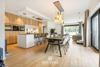 Voor meer info en foto’s, surf naar www.swevers.be – deze recente halfopen bebouwing in de Stationsstraat 85 D in Houthalen-Helchteren combineert ruimte, comfort en energiezuinig wonen op een uitstekende locatie. De woning werd gebouwd in 2019, is volledig instapklaar en afgewerkt met kwalitatieve, neutrale materialen. Met een bewoonbare oppervlakte van 203 m² op een zuidgericht perceel van 1.266 m² geniet u hier van veel licht, een praktische indeling en een aangenaam gevoel van rust. Op het gelijkvloers komt u binnen via de inkomhal met gastentoilet. Verder vindt u een ruime wasplaats, een ruime bureauruimte die ook kan dienen als gelijkvloerse slaapkamer, en een lichtrijke leefruimte van ongeveer 40 m² met zicht op terras en tuin. De open keuken van 14 m² is volledig uitgerust met hoogwaardige toestellen, waaronder een stoomoven, heteluchtoven, koffieapparaat, vaatwasser en inductiekookplaat. Aansluitend zijn er nog een berging en een extra hal met ingemaakte kasten. De verdieping telt nog vier volwaardige slaapkamers van 14 m², 12 m², 10,60 m² en 10,60 m², een extra bergruimte, een badkamer met douche en dubbele lavabo, en een apart toilet. Dankzij de vele praktische bergruimtes is elke vierkante meter optimaal benut. Buiten geniet u van een ruime, zuidgerichte tuin met blijvend groen verzicht achteraan door het aangrenzende agrarische gebied. Extra troeven zijn vloerverwarming, zonnepanelen, warmtepomp, domotica en screens aan de achterzijde. Bovendien wordt er binnenkort een elektrische poort geplaatst. Winkels, scholen, openbaar vervoer en snelwegen bevinden zich vlakbij. Voor meer informatie, bel 011 255 155. Bron bewoonbare oppervlakte: EPC – verslag.