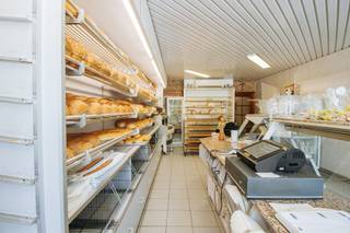 <p>In het hart van Rumst, op een opvallende en vlot bereikbare locatie onder de kerktoren, biedt zich een unieke kans aan: de <strong>overname van een gevestigde bakkerij mét het bijhorende eigendom</strong>. Deze authentieke handelszaak geniet al jaren een sterke lokale verankering en combineert een instapklare professionele activiteit met comfortabel wonen op dezelfde locatie.</p><p><br /></p><p>Je komt binnen in de winkelruimte, die vandaag praktisch is ingericht maar tegelijk makkelijk aangepast kan worden aan eigen wensen. De typische geur van vers gebakken brood maakt meteen duidelijk dat dit een plek is met geschiedenis en ambacht. Achteraan ligt de bakkerij zelf, uitgerust met kwalitatieve ovens, kneedmachines en rijskasten — alles wat nodig is om meteen aan de slag te gaan.</p><p>Achter het gebouw is er nog een garage en een aangenaam tuintje, handig voor leveringen of gewoon als rustige buitenruimte. Met de Nete als achterbuur kom je hier bovendien helemaal tot rust.</p><p>Boven de zaak bevindt zich een duplex appartement dat mee is met zijn tijd, met onder andere drie slaapkamers en het comfort dat je vandaag verwacht.</p><p>Een mooie opportuniteit voor wie droomt van een eigen zaak met karakter, of voor een bestaande bakker die zich verder lokaal wil verankeren op een sterke locatie.</p><p><br /></p><p><strong>Troeven: </strong>Centrale ligging – Instapklare bakkerij – Wonen en werken te combineren – Authentiek karakter – Rustige achterzijde</p>