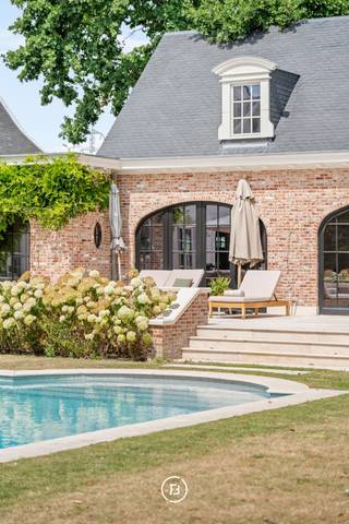 Deze karaktervolle Franse villa, ontworpen door architect Jules Delarue, onderging in 2021 een totaalrenovatie waarbij authenticiteit en hedendaags comfort harmonieus werden samengebracht. Een eigendom waar ruimte, licht en verfijnde materialen centraal staan.<br /><br />De woning biedt royale leefruimtes met een tijdloze uitstraling, gekenmerkt door onder meer marmeren vloeren, parket, sierlijsten en een sfeervolle haard. De leefkeuken werd uitgerust met hoogwaardige Miele toestellen en vormt samen met het verfijnde maatwerk een mooi geheel. <br /><br />De eerste verdieping omvat vier slaapkamers, drie badkamers en een ruime dressing. Daarnaast beschikt de woning over een volledig onderkelderde verdieping met tal van praktische ruimtes en een tweede bovenverdieping die polyvalent kan worden ingericht als bureau, speelruimte, extra slaapkamers of cinemaruimte.<br /><br />Ook buiten werd een bijzonder kwalitatief totaalconcept gerealiseerd. De aangelegde tuin met terrassen in oud marmer, het stijlvolle zwembad en het afzonderlijk toegankelijke poolhouse creëren een unieke woonbeleving. Het poolhouse, afgewerkt met eikenhout, natuursteen en vloerverwarming, leent zich perfect als kantoor, atelier of ontspanningsruimte.<br /><br />Een uitzonderlijke eigendom waar karaktervolle architectuur, hoogwaardige afwerking en een aangename connectie met de buitenomgeving samenkomen.