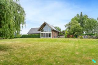 Gelegen in een landelijk gebied en omringd door uitgestrekte velden vinden we deze unieke ééngezinswoning terug.<strong> </strong>De verborgen parel is gelegen op een perceel van 12.816 m² en beschikt over een bewoonbare oppervlakte van 326m² (volgens EPC-attest). Ongeveer de helft van het perceel werd omgezet in bebossing, waardoor het tuinonderhoud een pak interessanter wordt. De woning is volledig onderkelderd en beschikt over een dubbele garage, voorraadkamer en polyvalente (opslag)ruimte. Inkomhal met vestiaire en gastentoilet, woonkamer met fantastisch zicht op de tuin, hyper geïnstalleerde keuken met aansluitend (overdekt) terras en annex berging/wasplaats. Open ruimte boven leefgedeelte, aansluitend de master bedroom met naastliggende slaapkamer die kan omgevormd worden tot badkamer (afvoer en toevoer voorzien). In de andere vleugel van de woning bevinden zich de drie overige slaapkamers en de geïnstalleerde badkamer. Volledig omheinde tuin, riante oprit met geautomatiseerde poort, inrijhelling voor garages in kelder, aparte garagebox, opbouwzwembad met sturing en de gezellige chalet. Het bijgebouw bestaat uit een apart toilet, leefruimte met keuken en aansluitend de slaapkamer met douche en wastafel. CV op aardgas (HR ketel 2021) | HR beglazing aluminium | EPC label B | Warmtepomp (airco) in leefruimte en alle slaapkamers | Zonnepanelen 12.390 Wp. Laurence (BIV 541 501) organiseert voor deze woning de bezoeken, mits het maken van een afspraak.