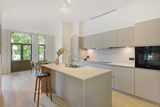 In een kleinschalig historisch hoekgebouw, dat met respect voor zijn karakter volledig werd gerenoveerd, bevindt zich op de eerste verdieping dit bijzonder aangename en lichtrijke appartement met twee slaapkamers.<br /><br />Bij het binnenkomen vallen meteen de royale plafondhoogte, de grote raampartijen en het open karakter van de leefruimte op. Vooraan geniet het appartement van een mooi en groen uitzicht over enkele karaktervolle burgerhuizen en het plein aan de Onze-Lieve-Vrouw-Geboortekerk. De grote ramen halen het daglicht rijkelijk naar binnen en versterken het ruimtelijke gevoel. Aansluitend aan de leefruimte bevindt zich bovendien een compact maar charmant sierterras.<br /><br />De open keuken vormt één geheel met de leefruimte en werd ingericht met een centraal eiland en alle nodige toestellen. Doorheen nagenoeg het volledige appartement werd een mooie parketvloer gelegd, met uitzondering van de vochtige ruimtes, wat zorgt voor een warme en stijlvolle uitstraling.<br /><br />Via de nachthal bereiken we de ruime badkamer met inloopdouche, een afzonderlijk toilet en twee volwaardige slaapkamers van ca. 12,5 m² en 9 m². Beide slaapkamers bevinden zich aan de rustige zijde van de d’Urselstraat. Vanuit de nachthal is er bovendien toegang tot een aangename extra buitenruimte (+-10m²) om in alle rust van de buitenlucht te genieten.<br /><br />Ook praktisch heeft dit appartement heel wat te bieden. In de kelderverdieping beschikt het over een private kelderberging en in de gemeenschappelijke inkomhal is een fietsenberging voorzien.<br /><br />Een bijzonder geslaagd appartement waar historische charme, licht, ruimte en hedendaags wooncomfort mooi samenkomen.<br />Bovendien superenergiezuinig: EPC label A = 42kwh/m²! alsook conforme elektriciteit én individuele zonnepanelen.<br /><br />Heeft u interesse in deze woning? Neem dan contact met het kantoor van VB Vastgoed Hoboken op het nummer 03 337 50 70 of via <span>info@vbvastgoed.be</span><br /> 