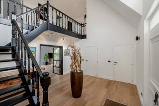 <p><strong>Riante gerenoveerde pastorijwoning met garage, studio en wellness op een perceel van ca. 5.400 m²</strong></p>
<p>Deze prachtige pastorijwoning werd volledig gerenoveerd en is gelegen op een ruim en privatief perceel van ca. 5.400 m². De woning combineert karakter met hedendaags comfort en beschikt over 4 à 5 slaapkamers, 3 badkamers, een ruime garage met studio en een aangelegde tuin met wellness.</p>
<p>De woning omvat:</p>
<ol>
<li>Een gelijkvloerse verdieping met o.a. inkomhal, leefruimte, open keuken, bureel/slaapkamer en badkamer.</li>
<li>Een eerste verdieping met meerdere slaapkamers en badkamers.</li>
<li>Een garagegebouw met studioverdieping.</li>
</ol>
<p><strong>Voorzieningen op het gelijkvloers:</strong><br />Deze woning is op het gelijkvloers voorzien van:<br />- Een ruime inkomhal op parket met vestiairekast en gastentoilet met handenwasser<br />- Een eerste slaapkamer met ensuite badkamer voorzien van inloopdouche, toilet en lavabo<br />- Een tweede kamer, ideaal als bureel of extra slaapkamer.<br />- Een lichtrijke leefruimte met open haard en grote schuiframen met toegang tot de tuin.<br />- Een open, volledig ingerichte keuken met o.a. dubbele spoelbak, vaatwasser, gasfornuis met oven, dampkap, Amerikaanse koelkast en wijnkoelkast.</p>
<p><strong>Voorzieningen op de eerste verdieping:</strong><br />De eerste verdieping bestaat uit:<br />- Twee ruime slaapkamers.<br />- Een badkamer met douche, toilet en lavabo, alsook aansluitingen voor wasmachine en droogkast.<br />- Een master bedroom met dressing en ensuite badkamer voorzien van ligbad, inloopdouche, dubbele lavabo en toilet.<br />- Twee praktische bergruimtes op de overloop.</p>
<p><strong>Garage en studio:<br /></strong>- Ruime inpandige garage met automatische poorten en plaats voor drie wagens.<br />- Boven de garage bevindt zich een studioverdieping, bereikbaar via een vaste trap.</p>
<p><strong>Tuin:</strong><br />Aangelegde en privatieve tuin bereikbaar via een automatische toegangspoort en lange oprit met parkeermogelijkheden voor meerdere wagens. De tuin beschikt over een siervijver met terras, een open achterliggend perceel met mooie bomen, een overdekt terras, een aanbouw met glaspartijen en een buitenwellness met sauna, douche en koelbad.<br />Tussen de woning en de garage bevindt zich een overdekte carport.</p>
<p><strong>Extra troeven:<br /></strong>- Zeer ruim perceel met veel privacy<br />- Groot bewoonbaar volume<br />- Drievoudige garage<br />- Veel lichtinval<br />- Kruipruimte onder de volledige woning<br />- Gunstig EPC</p>