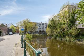 <strong>Hoekappartement met twee slaapkamers en ruim zonneterras.</strong><br /><br />Op de vijfde verdieping bevindt zich dit ruime en lichtrijke appartement met een aangenaam open gevoel.<br /><br />Het appartement beschikt over twee volwaardige slaapkamers, waarvan één slaapkamer is voorzien van een eigen douchekamer en terras met uitzicht op groen en water. In de nachthal bevindt zich bovendien een tweede, volwaardige badkamer.<br /><br />De lichtrijke leefruimte sluit aan op een ruim, zuidgericht terras. Een praktische berging in het appartement zorgt voor extra opbergruimte.<br /><br />Daarnaast beschikt het appartement over een private kelderberging en is er een gemeenschappelijke fietsenberging. Er is tevens de mogelijkheid om een ondergrondse autostaanplaats aan te kopen (€ 30.000).<br /><br />De ligging vormt een extra troef: vlot bereikbaar via de nabijgelegen invalswegen en uitstekend verbonden met de fietsostrade.