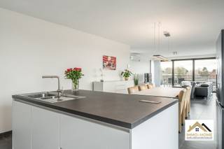 Vanuit dit prachtige penthouse bent u vanaf dag 1 ook de eigenaar van de volledige skyline van Wachtebeke-centrum. De bijzonder lichtrijke leefruimte met open keuken baadt in het daglicht door de grote raampartijen en zo ziet u vanuit elke hoek het dagelijkse leven in het dorp als een continue bewegend schilderij voorbij glijden - zonder er evenwel enige last van te ondervinden. De keuken is voorzien van alle moderne comfort, vanachter het ruime kookeiland is er eveneens altijd een bijzonder uitzicht. Net naast de keuken is er een grote opslagruimte/wasplaats aanwezig. Een lange gang (rechtstreeks bereikbaar met de lift en uiteraard ook via de trap) brengt je tot in de twee slaapkamers, waarvan de grootste is voorzien van een mooie dressing. De badkamer beschikt over een riante inloopdouche, en in de gang is er een apart toilet aanwezig. Van het buitenleven genieten doe je op het grote zonovergoten terras, dat via de schuifdeuren van de leefruimte bereikbaar is. Er is verplicht een garage aan te kopen voor €25 000 en een parkeerplaats in het gebouw inbegrepen de prijs. Nog 3 jaar vrijgesteld van OV. Inschrijvingen via mail naar tommy@immo-home.be, geen telefonische inschrijvingen! Volg ons op Fb en insta. Voor meer info: www.immo-home.be GRATIS SCHATTING GRATIS FINANCIEEL ADVIES