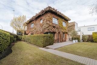 <p>In het geliefde Wilrijk, één van de meest gegeerde residentiële districten van Antwerpen, bevindt zich deze uitzonderlijke architecturale halfopen bebouwing, waar ruimte, licht en functionaliteit tot in de puntjes zijn uitgewerkt. Een unieke eigendom die wonen en werken op een bijzonder elegante manier verenigt.</p><p><br /></p><p>Bij het betreden van de woning kom je in een stijlvolle inkomhal. Aan de linkerzijde bevindt zich een volledig geïntegreerde praktijk- of kantoorruimte met eigen wachtzaal en apart toilet, discreet afgescheiden van het privéleven en ideaal voor vrije beroepen. Het woongedeelte verwelkomt je met een royale inkomhal en een vaste natuurstenen trap als architecturale blikvanger. Verder zijn er een vestiaire met gastentoilet en toegang tot de leefruimtes.</p><p>De lichtrijke keuken kijkt uit op de tuin en sluit naadloos aan op het leefgedeelte. Twee eetruimtes — een intieme plek en een ruimer eetgedeelte in het verlengde van de woonkamer — zorgen voor flexibiliteit en gezelligheid. Hoogwaardige materialen zoals de warme parketvloer en een strak ingebouwde zitbank geven de woning een moderne, verfijnde uitstraling.</p><p><br /></p><p>Op de bovenverdieping bevinden zich zes slaapkamers, waaronder een ruime master bedroom met aansluitende badkamer die ook toegankelijk is vanuit de gastenkamer. Daarnaast zijn er meerdere kamers die perfect kunnen dienen als bureau-, hobby- of slaapkamers. Achteraan bevindt zich een apart gedeelte met twee bijkomende slaapkamers en een badkamer, ideaal als gastenverblijf, tienerzone of extra werkruimte.</p><p><br /></p><p>De gezellige en private tuin vormt een verlengde van de woonruimtes en is deels aangelegd in stijlvol Meranti hout, wat zorgt voor een warme en luxueuze buitenbeleving. Verder beschikt de woning over een garage voor twee wagens, extra parkeergelegenheid op de oprit en een aparte fietsenstalling. Een zeldzame opportuniteit in Wilrijk voor wie op zoek is naar architecturale klasse, ruimte en een veelzijdige invulling.</p>