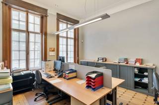 <strong>Schitterend herenhuis in eclectische stijl, gelegen in het centrum van Turnhout. Dit karaktervolle burgerhuis werd opgetrokken in 1935 naar een ontwerp van architect L. Van Ravestyn. De woning straalt authenticiteit en grandeur uit dankzij talloze bewaarde elementen zoals prachtige parketvloeren, glas-in-loodramen, hoge plafonds met rozetten en moulures,... De statige voorgevel met erker geeft de woning een unieke uitstraling. Gelegen op wandel- en fietsafstand van de Grote Markt, de winkelstraat en alle voorzieningen. Een ideaal eigendom op een centrale locatie – perfect voor wie op zoek is naar een stijlvolle woonst, kantoor of een vrij beroep aan huis.<br /><br /></strong><span>Gelijkvloerse verdieping:</span> Bij het betreden van de woning kom je terecht in een ruime inkomhal die meteen de toon zet met authentieke elementen en een warme, statige uitstraling. Binnenin wacht een indrukwekkende monumentale trapzaal met een statige eikenhouten trap en een prachtig glas-in-loodraam, die de grandeur van het interieur versterken. Vanuit de inkomhal is er toegang tot meerdere ruimtes, waaronder een ruim kantoor of ontvangstruimte aan de straatzijde – ideaal voor een vrij beroep of praktijk aan huis. <br /><br />Daarnaast zijn er nog twee royale kamers, momenteel ingericht als kantoor- en vergaderruimte. Dankzij hun flexibele indeling en elegante afwerking kunnen deze ruimtes echter ook perfect dienen als salon, eetkamer of leefruimte. Deze verdieping is dan ook uitermate geschikt voor zowel privégebruik als professionele doeleinden, met behoud van het authentieke karakter van de woning.<br /><br />Achteraan bevindt zich de ruimte keuken, die een directe verbinding heeft met het buitengebeuren. Deze buitenruimte doet momenteel dienst als parking met plaats voor maar liefst zes wagens en is bereikbaar via de Molenstraat. De buitenruimte kan perfect omgevormd worden tot een gezellige stadstuin. <br /><span><br />Eerste verdieping</span>: Op de eerste verdieping bevinden zich vier volwaardige kamers die momenteel dienst doen als kantoorruimtes. Elke kamer geniet van royale afmetingen, hoge plafonds en een overvloed aan daglicht dankzij de grote raampartijen en de centrale lichtschacht. Verder is er op deze verdieping een badkamer voorzien.<br /><br />Ook deze indeling biedt bijzonder veel flexibiliteit: de ruimtes kunnen eenvoudig worden ingericht als slaapkamers, hobbykamers of extra leefruimtes, afhankelijk van de noden van de bewoner.<br /><br /><span>Tweede verdieping</span>: De tweede verdieping telt eveneens meerdere volwaardige kamers, momenteel ingericht als bureauruimtes. Dankzij hun aangename afmetingen en de aanwezigheid van natuurlijk licht – onder andere via de lichtschacht – bieden ook deze ruimtes tal van mogelijkheden.<br /><br /><span>Bijzonderheden:</span> <br />- Volledig onderkelderd: archief en technische ruimte <br />- Airco <br />- Verwarming op stookolie d.m.v. radiatoren <br />- Achteraan parking (ca. 6 wagens) - bereikbaar via de Molenstraat<br />- Momenteel wordt het eigendom verhuurd aan € 5.427,83 per maand; de huurovereenkomst loopt nog twee jaar<br />- Het pand zit in een vennootschap – aandelen kunnen worden overgedragen<br /><br />Bekijk dit eigendom via onze interactieve grondplannen: https://deboerenpartners.virtimmocontent.be/start-visit/5323