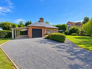 <p><span>Deze charmante, traditioneel gebouwde gedeeltelijk gelijkvloers villa ligt aan de zuidelijke rand van het zeer gegeerde Bois de Strihoux. </span></p><p><span>De villa omvat een inkomhal van 4 m² met gastentoilet (travertinvloer) die toegang geeft tot een leefruimte van 30 m² – eveneens met travertinvloer – waar een inbouwhaard op hout voor een gezellige sfeer zorgt. Aansluitend bevindt zich een moderne Ixina-keuken (10 m²) die naadloos overgaat in een lichtrijke veranda van 25 m² (voorzien van airconditioning), met kamerhoge ramen en een dakraam met drievoudige beglazing. Deze recente veranda vormt een natuurlijke overgang naar het beschutte terras en de grote tuin met op het zuiden oriëntatie. </span></p><p><span>Het slaapgedeelte is bereikbaar via een hal van 4 m² met luxe vinylvloer en omvat een hoofdslaapkamer van 14 m² met maatkasten, een tweede slaapkamer met airco (9 m²), een moderne inloopdouchekamer (6 m²) en een bureau (7 m²); vanuit het bureau leidt een trap naar een ruime derde slaapkamer van 26 m² met Velux-dakramen. In de betegelde garage van 16 m² bevinden zich de technische installaties, de boiler, de wasruimte en een koele berging. De woning werd in 1989 door de eigenaars zelf gebouwd (Huysmans Eeklo). Tot de uitrusting behoren onder meer een nieuwe condenserende mazoutketel (Riello, 2023), 10 zonnepanelen, een elektrische boiler, een B&G-inbouwhaard op hout, een regenwaterput, een grote carport voor twee wagens en twee tuinhuizen. Bieden vanaf € 550.000. Voor informatie en bezichtigingen kunt u bellen naar 02/355.50.55.</span></p><p><span> </span></p><p><span> </span></p>
