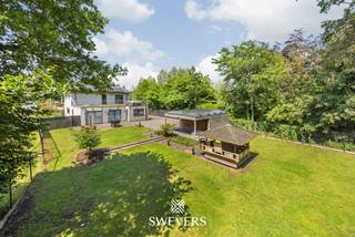 Voor meer info en foto’s, surf naar www.swevers.be – !! Via de 3D Tour Matterport kan u virtueel door het pand wandelen !! Deze instapklare open bebouwing in Diepenbeek combineert wonen en werken op een slimme manier. De woning uit 2010 is uitstekend onderhouden en telt 178 m² bewoonbare oppervlakte, aangevuld met een commerciële ruimte van 105 m² – ideaal voor zelfstandigen of vrije beroepen. De handelsruimte is gescheiden van het privé-gedeelte en voorzien van flexibele opzegmogelijkheden. Binnen geniet u van een ruime leefruimte (50 m²), een volledig uitgeruste keuken (15 m²), drie volwaardige slaapkamers – waarvan één met dressing – en een moderne badkamer. Extra troef: het riante dakterras van ca. 90 m² met jacuzzi. De zolder van 50 m² biedt uitbreidingsmogelijkheden. De kelderverdieping van 174 m² biedt ruime opbergmogelijkheden. Comfort is verzekerd met vloerverwarming, warmtepomp, zonnepanelen (EPC-label A), alarminstallatie en camerabewaking. Buiten geniet u van een zuidgerichte tuin met groen uitzicht en voldoende parkeergelegenheid dankzij een carport en inpandige garage van elk 25 m². U profiteert hier van een uiterst gunstige ligging met alle benodigde voorzieningen binnen handbereik. Voor meer informatie, bel 011 255 155. Bron bewoonbare oppervlakte: EPC – verslag.