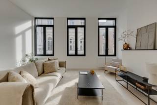 In het hart van Antwerpen bevindt zich dit hoogwaardig gerenoveerde appartement op de eerste verdieping. Een unieke woonbeleving waar elegantie, comfort en licht harmonieus samenkomen.<br /><br />Bij binnenkomst wordt u meteen verwelkomd door een gevoel van ruimte en rust. De afwerking werd met uiterste zorg gekozen, waarbij natuurlijke materialen, zachte kleuren en een tijdloos design zorgen voor een stijlvolle en serene woonomgeving.<br /><br /><span><strong>INDELING</strong></span>:<br /><br />Via de inkomhal betreedt u de uitzonderlijk lichtrijke leefruimte, waar grote raampartijen een overvloed aan natuurlijk licht binnenbrengen en een aangename sfeer creëren. <br /><br />De open leefruimte vloeit moeiteloos over in de volledig geïntegreerde designkeuken, uitgerust met kwalitatieve toestellen en verfijnde maatkasten in warme houttinten. <br /><br />De aansluitende eetruimte vormt een elegante plek om te tafelen en gasten te ontvangen.<br /><br />Het appartement beschikt over ruime, rustig gelegen slaapkamers die uitnodigen tot ontspanning. <br /><br />De badkamer werd afgewerkt met oog voor detail en biedt een stijlvolle inloopdouche en hoogwaardige materialen. <br /><br />Verder is er een apart gastentoilet en een praktische bergruimte aanwezig.<br /><br /><span><strong>BIJZONDERHEDEN</strong></span>:<br /><br />- Volledig en kwalitatief gerenoveerd met oog voor detail<br />- Gelegen op de eerste verdieping (zonder lift)<br />- Uitermate lichtrijk dankzij grote raampartijen<br />- Hoogwaardige, duurzame materialen en verfijnde afwerking<br />- Gegeerde centrumligging nabij winkels, gastronomie en openbaar vervoer