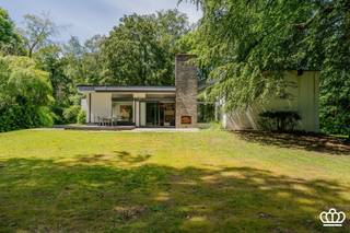 <p><span>Modernistische design villa, prachtig en residentieel gelegen te Kapellen, met 3 / 4 slaapkamers, 2 badkamers en inpandige garage op een mooi en open perceel met veel privacy van 6.355 m². </span></p><p><span>INDELING</span></p><p><span>Gelijkvloers:<br />Het gehele huis heeft een typisch zeer open en licht karakter, alle leefruimtes staan in open verbinding met elkaar en rondom voorzien van grote raampartijen die vrij uitzicht bieden over de prachtige tuin.</span></p><p><span>Inkomportaal met ingebouwde bloembak op wit marmer, overgaande in de inkom met vestiairehoek en gastentoilet. Inkom gaat over in een bilbliotheek / tv hoek op marmer met inbouwkasten, aansluitend zithoek met openhaard op parket, door een klein niveau verschil overgaand in een salon en eetkamer op parket en aanpalende open keuken voorzien van alle hedendaagse inbouwapparatuur en natuurstenen werkblad.    </span></p><p><span>Verdieping + 1/2:<br />Via een open trap toegang tot de galerij op de halve verdieping die uitgeeft op een masterbedroom bestaande uit slaapkamer, dressing en badkamer uitgerust met ligbad, douche, toilet, bidet en 2 lavabo’s. Verder nog 2 slaapkamers die een 2e badkamer delen, voorzien van ligbad, douche, toilet, bidet en 2 lavabo’s. De gehele verdieping, met uitzondering van de badkamers, is op tapijt.</span></p><p><span>Verdieping -1/2:<br />Middels dezelfde open trap toegang tot een gang die uitgeeft op de inpandige garage voor 2 wagens met automatische poort en aansluitingen voor wasmachine en droger. Een bergkamer, momenteel in gebruik als strijkkamer, een stookruimte en een atelierruimte welke eventueel is in te richten als extra (slaap)kamer met mogelijke doucheruimte. Achter inkomhal met toilet en toegang tot de kelder. </span></p><p><span>Kelder:<br />De gehele leefverdieping is onderkelderd, bestaande uit een betegeld deel met een wijnkelder en voorraadkelder.  Via een doorgang toegang tot de onafgewerkte bergkelder (122 m²). </span></p><p><span>Tuin:<br />Volwassen parktuin met fraaie bomenstand, rondom de villa zijn diverse terrassen, deels te overdekken met groot zonnescherm, vijver/waterpartij in het terras. In de tuin bevindt zich een ouder zwembad dat momenteel is omgevormd tot een vijver. De geniet volledige privacy en veel zoninval rond de villa. </span><span>In de tuin bevinden zich nog 2 houten tuinbergingen.</span></p><p><span>Overig / Bijzonderheden:<br />-Villa in fraaie seventies design stijl<br />-Bijzonder mooi gelegen in een residentiele wijk nabij het dorpscentrum van Kapellen met winkels, scholen, treinstation, ...<br />-De villa heeft veel potentieel maar is aan renovatie toe.<br />-CV op mazout</span></p><p><span> </span></p><p><span> </span></p>