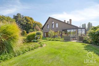 Deze strategisch gelegen open bebouwing biedt een <strong>bewoonbare oppervlakte</strong> van maar liefst<strong> 490 m²</strong>, op een perceel van <strong>32a37ca</strong>, met een weids <strong>uitzicht over agrarisch gebied</strong>. Met<strong> vijf ruime slaapkamers</strong> en de mogelijkheid om <strong>drie bijkomende kamers</strong> in te richten, biedt deze woning bijzonder veel mogelijkheden.<br /><br />Het gelijkvloers omvat een centrale hal, een lichtrijke woonkamer, keuken, veranda en bergruimte. Daarnaast bevinden zich hier drie slaapkamers, een badkamer, twee toiletten en een ruime garage. De slaapkamers en badkamer op dit niveau maken de woning ook aantrekkelijk voor wie comfortabel op het gelijkvloers wil wonen.<br /><br />Op de verdieping vindt u een ruime badkamer, twee ingerichte, royale slaapkamers en zolderruimten. Mits verdere afwerking kunnen deze worden ingericht als drie extra slaapkamers, een mancave, hobbyruimte of een combinatie hiervan.<br /><br />Ook op technisch vlak heeft deze villa heel wat te bieden: de woning is <strong>asbestveilig </strong>en beschikt over dakisolatie, dubbele beglazing, gunstig epc <strong>label C – 247 kWh/m²</strong> (geen renovatieplicht!), centrale verwarming op aardgas, een gaskachel en een warmtepomp. De <strong>34 zonnepanelen</strong> met <strong>groenestroomcertificaten </strong>en de regenwaterput van 20.000 liter vervolledigen het geheel.<br /><br />Parkeren kan op de ruime <strong>parkeergelegenheid </strong>voor en naast de woning, in de <strong>garage </strong>of onder de <strong>carport</strong>. Eveneens is er een prachtig aangelegde tuin met vijver en terrassen waar het heerlijk vertoeven is.<br /><br />De villa is <strong>strategisch gelegen</strong>, vlak bij een bushalte, op 4,4 km van het station en 7 km van de oprit van de E19. Alsook in omgeving van winkels en scholen.<br /><br />Een villa met uitzonderlijk veel ruimte, een groen vergezicht en volop mogelijkheden om wonen, werken en hobby’s te combineren. Contacteer ons voor meer informatie of een bezoek: 054 23 53 83 of info@localsvastgoed.be