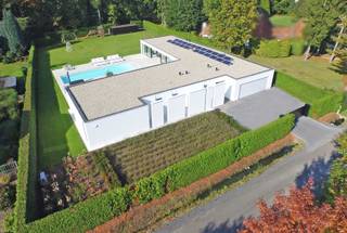 <p><span>Op een prachtig perceel van maar liefst ±30 are, volledig omheind en met optimale privacy, bevindt zich deze uitzonderlijke architecturale laagbouwvilla uit ±2014. Deze moderne L-vormige villa, ontworpen door UAU Architecten, combineert tijdloze elegantie met een ongeëvenaard wooncomfort.</span></p><p><span> </span></p><p><span>De woning onderscheidt zich door haar strakke architectuur en de indrukwekkende glazen achtergevel. Elke leefruimte baadt in natuurlijk licht en geniet van een prachtig zicht op de tuin en het zwembad. Hier ervaart u elke dag opnieuw een vakantiegevoel!</span></p><p><span> </span></p><p><span>Bij binnenkomst verwelkomt de ruime inkomhal met vestiaire en gastentoilet u in een woning waar luxe en functionaliteit perfect samenkomen. De royale leefruimte vormt het hart van de woning. Deze omvat een living met gashaard en tv-hoek, een ruime eetplaats en een hoogwaardige open keuken met centraal kookeiland, dubbele vaatwasser, ingebouwd koffieapparaat en kwalitatieve Miele-toestellen. Aansluitend bevindt zich een uitzonderlijk grote bijkeuken die extra comfort biedt.</span></p><p><span> </span></p><p><span>Een op maat gemaakte kastenwand met geïntegreerd bureau vormt de verbinding tussen de leefruimte en een polyvalente ruimte. Deze is momenteel ingericht als fitnessruimte, maar kan eveneens perfect dienstdoen als gastenverblijf. De ruimte beschikt over een eigen douche, toilet en wastafel. Ook de nodige voorzieningen voor de installatie van een sauna zijn aanwezig. </span></p><p><span> </span></p><p><span>Het nachtgedeelte bevindt zich in de andere vleugel van de woning en garandeert optimale rust. Hier bevinden zich een bureau- of hobbyruimte en twee ruime kinderkamers, elk voorzien van een eigen douchekamer, toilet, bureau en ingebouwde kasten. De luxueuze mastersuite beschikt bovendien over een ruime inloopdressing en een privébadkamer met inloopdouche en vrijstaand ligbad. </span></p><p><span> </span></p><p><span>De villa onderscheidt zich door haar bijzonder praktische indeling, waarbij elke vierkante meter optimaal wordt benut. Dankzij de volledig ingebouwde afwerking en maatwerkkasten geniet u van maximaal comfort en veel bergruimte.<br /><br />Het zwembad van 15 meter op 5 meter wordt omringd door een ruim zonneterras. Het overdekte terras (5 op 5 m) biedt de ideale setting om het hele jaar door te genieten van het buitenleven, steeds met volledige privacy en een perfecte westoriëntatie.</span></p><p><span> </span></p><p><span>Ook op technisch vlak voldoet deze villa aan de hedendaagse normen. De woning is voorzien van onder meer over 22 zonnepanelen, een laadpaal voor elektrische voertuigen, vloerverwarming, een ventilatiesysteem en een warmtepomp voor zowel airconditioning als zwembadverwarming.</span></p><p><span> </span></p><p><span>Verder beschikt de villa over een dubbele inpan</span><span>dige garage met inbouwkasten. </span></p><p><span> </span></p><p><span>Een unieke eigendom voor wie op zoek is naar architectuur, luxe, ruimte en absolute rust nabij stad! </span></p><p><span> </span></p>