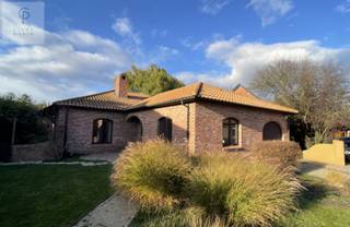 Via het beklinkerde tuinpad begeven we ons naar de centrale inkomhal van deze mooie bungalow. De inkomhal met gastentoilet geeft doorgang tot...