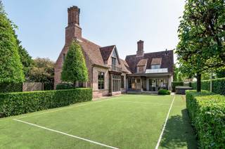 <p><span>Ruime villa in Engelse Cottage stijl nabij het centrum van Hoogstraten</span></p><p><span> </span></p><p><span>U betreedt de villa middels de centrale inkomhal met gastentoilet en trap naar de verdieping, middels de dienstgang toegang tot de inpandige garage. Vanuit de inkomhal ook toegang tot de leefruimte, welke bestaat uit een zitgedeelte met TV hoek, ruime woonkamer met open haard en aansluitende eetkamer met zicht op de tuin. Vanuit de eetkamer toegang tot de ruime leefkeuken welke is uitgerust met diverse inbouwtoestellen en een groot werkeiland. Via de keuken ook een doorgang met berging en sanitaire ruimte naar de aparte vleugel, welke dienst kan doen als bijkomende leefruimte, kantoor of atelier. De separate zij-ingang biedt een aparte inkomhal met nog een gastentoilet en toegang tot de eerder genoemde aparte vleugel of kantoor, alsook een trap naar de verdieping boven deze ruimte. </span></p><p><span> </span></p><p><span>Verdieping</span></p><p><span>Middels de trap in de centrale inkom bereikt u de nachthal met toegang tot de hoofdslaapkamer, een ruime badkamer, een dressingkamer of bijkomende kamer, nog twee slaapkamers. Via een aparte trap vanuit de zij inkom bereikt u de polyvalente ruimte boven de tweede living of atelier. </span></p><p><span> </span></p><p><span>Bijgebouw</span></p><p><span>Achteraan op het terrein bevindt zich een prachtig bijgebouw met een polyvalente leefruimte op het gelijkvloers en twee garageplaatsen, alsook een guestroom op de verdieping als gastenverblijf of ruimte voor au-pair. </span></p><p><span> </span></p><p><span>Carport</span></p><p><span>Naast het grote bijgebouw bevindt zich nog een ruime carport met berging. </span></p><p><span> </span></p><p><span>Tuin en buitenruimtes</span></p><p><span>Achter de woning bevinden zich ruime terrassen met veel lichtinval alsook de aangelegde tuin met polyvalent sportveld. Aan de voorzijde van de villa werd een onderhoudsvriendelijke tuin gerealiseerd in harmonie met de stijl van de woning. De oprit loopt langs de villa naar de achtergelegen bijgebouwen en garage/ carport.</span></p><p><span> </span></p><p><span>Bijzonderheden</span></p><p><span>Deze smaakvolle en karaktervolle villa biedt zeer veel mogelijkheden zoals een combinatie wonen en werken, grote familie, kunstatelier etc. </span></p><p><span>De aanwezige aparte vleugel als kantoor of gastenverblijf heeft een eigen "huisnummer" en gescheiden nutsvoorzieningen en is dus zeer geschikt als kantoor aan huis of co-housing.</span></p><p><span>Bij de totaal renovatie in 2009 werd de villa bijna volledig opnieuw gebouwd met gebruik van hoogwaardige materialen en historische bouwmaterialen. </span></p><p><span> </span></p><p><span>Meer inlichtingen via ons kantoor</span></p><p><span> </span></p>
