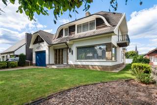 Goed onderhouden vrijstaande woning in Franse stijl met inpandige garage.Via de inkomhal, voorzien van een trap naar de bovenverdieping, bereik je de...