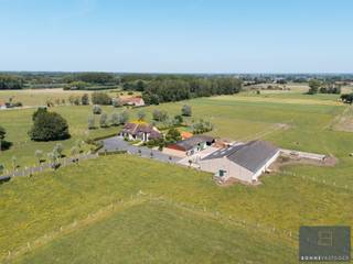<p>Op een <strong>uitzonderlijke topligging aan de flanken van de Oedelemberg</strong> ontvouwt zich deze karaktervolle boerderij, omgeven door uitgestrekte weides en pure natuur. Hier ervaar je een <strong>zeldzame combinatie van open vergezichten, absolute rust en maximale privacy</strong>, op een perceel van maar liefst <strong>1,5 hectare</strong>. Een plek waar stilte, ruimte en authenticiteit samenkomen.</p>
<p>De woning zelf imponeert door haar <strong>royale volumes en doordachte indeling</strong>. Via de inkomhal krijg je toegang tot enerzijds een ruime leefruimte en anderzijds een afzonderlijk bureau, ideaal voor thuiswerk of een vrij beroep. De leefruimte sluit naadloos aan op de bijzonder grote keuken, die uitgroeit tot het hart van het huis. Hier vind je niet alleen een gezellige ontbijthoek, maar ook een extra zithoek, een praktische berging en een volwaardige bijkeuken. Grote raampartijen zorgen voor een <strong>adembenemend uitzicht op de tuin en de omliggende weilanden</strong>, dat nooit verveelt.</p>
<p>Op het gelijkvloers is verder een badkamer voorzien, een tweede inkom met gastentoilet, een zeer ruime was- en technische ruimte én een dubbele inpandige garage. Alles is opgevat met het oog op comfort en functionaliteit.</p>
<p>De verdieping biedt plaats aan <strong>drie uitzonderlijk ruime slaapkamers</strong> en een grote badkamer. Dankzij de overvloedige ruimte zijn hier moeiteloos <strong>extra slaapkamers of badkamers</strong> te realiseren, volledig naar eigen wens.</p>
<p>Het erf omvat daarnaast meerdere <strong>solide bijgebouwen en stallen</strong> met oppervlaktes van ongeveer 600 m², 250 m² en 175 m², aangevuld met een <strong>vergunde mestput</strong>. De eigendom wordt vandaag nog uitgebaat als agrarisch bedrijf (rundveehouderij) en beschikt over de nodige vergunningen. Gelegen in <strong>landschappelijk waardevol agrarisch gebied</strong>, zonder opname op erfgoedlijsten, biedt dit pand tal van mogelijkheden.</p>
<p>Verder beschikt het geheel over <strong>duurzame voorzieningen</strong>, waaronder twee regenwaterputten van 5.000 liter, een gemetste waterput met pomp en <strong>meer dan 60 zonnepanelen</strong> op de stal naast de woning.</p>
<p>Voor wie nóg meer ruimte wenst, bestaat de mogelijkheid om de <strong>aangrenzende weilanden aan te kopen</strong>, goed voor een totale oppervlakte van <strong>6,28 hectare</strong>.</p>
<p>Een <strong>unieke eigendom</strong> voor wie groots wil wonen, werken of ondernemen, midden in het groen en ver weg van de drukte.</p>
<p>Voor meer informatie of het inplannen van een bezoek, aarzel niet om ons te contacteren via info@bonnevastgoed.be of via 050/73.73.73.</p>