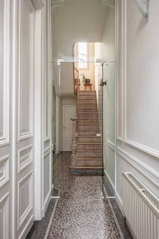 Wonen op één van de meest gegeerde locaties van Antwerpen? Dit charmante, compacte herenhuis bevindt zich in het geliefde Zurenborg, een buurt die bekendstaat om haar prachtige architectuur, gezellige straten en bruisende sfeer.
Op wandelafstand vind je tal van populaire koffiebars, restaurants en gezellige horecazaken, terwijl ook het stadscentrum en belangrijke invalswegen vlot bereikbaar zijn. Een ideale uitvalsbasis voor wie houdt van het stadsleven, maar tegelijk wil thuiskomen in een karaktervolle en aangename woonbuurt.
De woning zelf combineert authentieke elementen met een verrassend open vloerplan. De huidige indeling biedt een fijne ruimtelijkheid, maar laat tegelijk verschillende mogelijkheden toe om de woning volledig naar eigen smaak en woonbehoeften in te richten.
Bij het binnenkomen verwelkomt de inkomhal je meteen met authentieke vloertegels die de sfeer van het huis perfect neerzetten. Van hieruit wandel je door naar de eetkamer, met vooraan de keuken. Achteraan bevindt zich de eerste badkamer, ingericht met een douche, toilet en aansluitend een praktische inloopdressing.
De karaktervolle, gezandstraalde trap leidt naar de eerste verdieping. Deze werd momenteel volledig opengewerkt en combineert een eerste slaapkamer met de leefruimte. Wie liever afzonderlijke kamers creëert, kan deze verdieping eenvoudig opnieuw opdelen. Authentieke details en een prachtige ingebouwde boekenkast zorgen hier voor extra cachet.
Op de tweede verdieping bevindt zich de tweede slaapkamer, voorzien van ingemaakte kasten. De open badkamer geeft deze verdieping een bijzonder loftgevoel en is uitgerust met zowel een ligbad als een douche.
Een woning voor liefhebbers van karakter, open ruimtes en authentieke details, op een locatie die moeilijk te evenaren is. Compact in oppervlakte, maar bijzonder in uitstraling én mogelijkheden.
Een charmante stadswoning met een eigenzinnig karakter, midden in het geliefde Zurenborg.