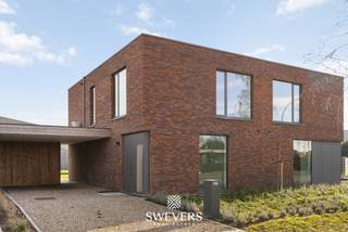 In een rustige woonwijk in het groene Leopoldsburg ontdek je deze stijlvolle halfopen nieuwbouwwoning, gebouwd in 2025. Met een moderne uitstraling, functionele indeling en energiezuinige aanpak vormt deze woning de perfecte match voor gezinnen, koppels of wie gewoon op zoek is naar hedendaags wooncomfort. Hier woon je in alle rust, maar toch vlak bij alles wat je nodig hebt.<br /><br />De woning heeft een bewoonbare oppervlakte van 158,40 m² en is gespreid over twee volwaardige bouwlagen. Dankzij het doordachte ontwerp voelt elke ruimte open en licht aan. De woning werd recent opgeleverd en is volledig instapklaar. Dit betekent: geen renovatiewerken, geen zorgen — gewoon verhuizen en genieten.<br />Op de gelijkvloerse verdieping bevindt zich een ruime inkomhal met vestiairemogelijkheid en gastentoilet. Van daaruit wandel je zo door naar de leefruimte van 44 m², die dankzij haar open karakter bijzonder uitnodigend aanvoelt. <br /><br />De grote glaspartijen zorgen niet alleen voor een overvloed aan daglicht, maar geven ook directe toegang tot het terras en de zuidoostelijk georiënteerde tuin. Achteraan is er voldoende ruimte voor kinderen om te spelen of om in alle rust te genieten van een zonnige ochtendkoffie. De aangrenzende keuken van 18 m² biedt plaats voor een gezellige ontbijthoek en is praktisch ingericht met zicht op de tuin. Aansluitend is er nog een inpandige berging van 3,84 m², ideaal voor voorraad of wasmachine.<br /><br />Boven zijn drie slaapkamers voorzien, telkens met voldoende lichtinval en ruimte voor kasten en bureau. De master bedroom meet 14 m² en is perfect voor een groot tweepersoonsbed en extra opbergruimte. De andere twee slaapkamers (beide 11 m²) zijn ideaal als kinderkamer, logeerkamer of thuiskantoor. De kamers bevinden zich rond een centrale nachthal, die ook toegang geeft tot een comfortabele badkamer. Deze is 7,03 m² groot en voorzien van een dubbele lavabo, toilet, ligbad en aparte douche — alles wat je nodig hebt om de dag ontspannen te starten. <br />Extra opbergruimte is voorzien in een tweede berging van 5,44 m², handig voor was- en strijkmateriaal of als seizoensopslag.<br /><br />Dankzij de afwezigheid van een kelder of zolder worden alle functionele ruimtes benut op de twee bestaande woonlagen. Dit zorgt voor een overzichtelijke woning zonder verloren vierkante meters.<br /><br />Met een perceel van 321 m² geniet je van een tuin op mensenmaat. De oriëntatie naar het zuidoosten garandeert zon van 's ochtends tot in de vroege namiddag. De perfecte plek om een terras aan te leggen, een speelplek voor de kinderen te creëren of een rustige hoek in te richten om te ontspannen met een boek. Een carport naast de woning biedt ruimte voor een wagen, met extra plaats voor fietsen of tuinmateriaal.<br /><br />Naast de functionele indeling en het moderne wooncomfort is het vooral de ligging die deze woning extra aantrekkelijk maakt. Op slechts 200 meter bevinden zich scholen, ideaal voor jonge gezinnen. Het station ligt op amper 650 meter, wat zorgt voor een vlotte verbinding richting onder andere Hasselt of Antwerpen. Restaurants, winkels en sportinfrastructuur zijn bereikbaar op minder dan een kilometer. En de snelweg? Die bereik je binnen de tien minuten.<br /><br />Bovendien biedt deze woning een voordelig fiscaal voordeel: de grondwaarde bedraagt € 90 000 (12% registratierechten), terwijl de constructiewaarde van € 294 500 onder het 6 % btw-tarief valt.<br /><br />Deze woning combineert hedendaags wooncomfort met een slimme indeling, gunstige ligging en een zonnige tuin. Volledig nieuw, perfect afgewerkt en klaar voor de toekomst. Wil je het zelf ervaren? Bel ons vandaag nog voor een afspraak op 011 255 155 en ontdek de mogelijkheden tijdens een persoonlijke rondleiding. Bron bewoonbare oppervlakte: EPC – verslag.