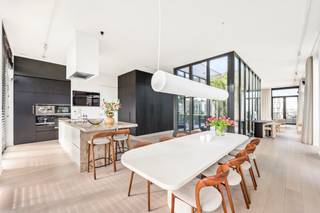 <p>In de skyline van Antwerpen, op ’t Eilandje, bevindt zich deze buitengewone penthouse. Een woning die architecturale ambitie en verfijnde luxe verenigt op een manier die zeldzaam is. <br /><br />De leefruimte strekt zich uit over een indrukwekkende oppervlakte en baadt in natuurlijk licht via kamerhoge raampartijen, met zicht op Antwerpen en het Kattendijkdok. Het hart van de woning is een architecturale blikvanger, een glazen atrium dat buiten naar binnen brengt als een groene oase, waarrond de woonkamer zich vormt.<br />Een ruime eetkamer sluit aan op de open keuken. Het kookeiland is afgewerkt in marmer, een natuursteen die warmte en levendigheid in zich draagt. Volledig geïntegreerde Miele-apparatuur, inclusief stoomoven, mircogolf, oven en koffieapparaat, samen met een Quooker-kraan, maken van koken een verfijnde ervaring.<br />De ingemaakte kastenwand in zwart eik verbindt de ruimtes en voegt een ingetogen luxe toe die diepte en karakter geeft. Van hieruit vloeit de ruimte naadloos over in het salon, waar de ingebouwde open haard subtiel de aandacht trekt.<br />De terrassen rondom de leefruimte en slaapkamers creëren een groene buffer en bieden verschillende plekken om te genieten van zon en stadszichten.<br />De masterbedroom beschikt over een ensuite badkamer afgewerkt met marmer en uitgerust met Vola-kraanwerk, dubbele lavabo, inloopdouche en whirlpoolbad. De kamer is voorzien van airconditioning. De twee extra slaapkamers lenen zich perfect als slaapruimte of thuiswerkplek. Een bijkomende douchekamer, eveneens afgewerkt met Vola-kraanwerk en marmer, zorgt voor extra comfort.<br />De absolute kroon is het zonnige dakterras, omgeven door weelderig groen, met lounge- en eetzone en panoramisch uitzicht over het Eilandje. Een ingebouwde sauna maakt dit terras een plek voor ontspanning in elk seizoen.<br />Bijkomend werd geopteerd voor een PV-installatie van 20 panelen en een thuisbatterij om de energiezuinigheid te verduurzamen. <br />Verder wordt het wooncomfort verhoogd met een afgesloten garagebox, met ruime berging, voor vier wagens in de ondergrondse parkeergarage dewelke aan te kopen is voor 150.000 euro. <br /><br /><span>Het Eilandje is bovendien Antwerpen op haar allerbest: het MAS op wandelafstand, de beste restaurants en koffiebars in de directe nabijheid, en de rust van het water als constante metgezel. </span><br /><br /></p>