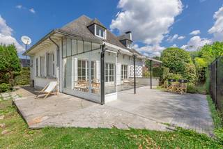 <p><strong>Karaktervolle villa op rustige, residentiële ligging in Dilbeek - deelgemeente Schepdaal</strong></p>
<p>In een aangename en rustige straat, vlakbij belangrijke invalswegen, treffen we deze statige villa op een perceel van 10 are. De woning dateert uit 1965 en biedt een solide basis voor wie op zoek is naar ruimte, charme en een rustige, groene omgeving.</p>
<p>De villa bevindt zich in een degelijke staat, al is een <strong>energetische renovatie</strong> vereist. Zo zijn onder meer de dakconstructie, verwarmingsketel en enkele houten ramen met enkel glas toe aan vernieuwing.</p>
<p><strong>Indeling</strong><br />Via de ruime inkomhal bereik je de grote en lichtrijke leefruimte met eetplaats, salon met houtcassette en een aangename bureauhoek. De gesloten keuken werd in 2017 vernieuwd en biedt alle comfort.<br />De mooie houten trap brengt je naar de eerste verdieping met afzonderlijk toilet, drie slaapkamers (12,5m², 14m² en 15m²) waarvan enkele met ingebouwde kasten, een vernieuwde douchekamer (3 m²) en een ruime badkamer.<br />De zolder is bereikbaar via een uittrekbare trap en kan gebruikt worden als stockagezolder.</p>
<p>De kelderverdieping is bijzonder praktisch ingedeeld en omvat een inpandige garage (ca. 22 m²), een wijn-/proviandkelder (9 m²) en een royale wasplaats (25 m²).</p>
<p>De leefruimte sluit naadloos aan op het zonnige terras en de achterliggende tuin met volgroeide bomen. Van hieruit heb je eveneens toegang tot het afzonderlijke garagegebouw, die ook kan worden ingericht als atelier, bergplaats of poolhouse.</p>
<p><strong>EPC:</strong> 877 kWh/m²/jaar – Klasse F<br /><strong>Elektriciteit:</strong> niet conform<br /><strong>Asbestattest:</strong> niet asbestveilig</p>
<p>Deze karaktervolle villa vormt een uitstekende opportuniteit voor wie wil investeren in een ruime woning op een toplocatie in Schepdaal, met alle troeven om er een prachtige, toekomstgerichte thuis van te maken.</p>