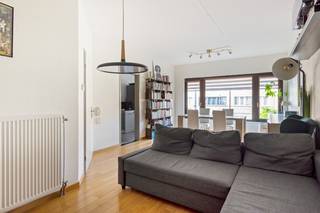 DE PRIJS IS INCLUSIEF DE GARAGEBOX - Dit instapklaar appartement op de 1e verdieping is gelegen is een aangename woonwijk in Hoevenen. Hoewel het hier rustig wonen is, zijn winkels, openbaar vervoer en scholen toch allen in de directe omgeving te vinden. U komt het appartement binnen via een aparte inkomhal met vestiairehoekje. Vanuit de hal heeft u meteen toegang tot de lichtrijke woonkamer met warmtepomp en aangrenzende, comfortabel uitgeruste keuken aan de voorzijde van het appartement. Verder beschikt de flat nog over een badkamer met douche en wastafel met marmeren blad en bijpassend meubel, een apart toilet, een kleine berging en 2 volwaardige slaapkamers, waarvan 1 uitgerust is met een warmtepomp. Achteraan bevindt zich nog een klein balkon, dewelke toegankelijk is vanuit de grote slaapkamer. Bij het appartement hoort verder nog een privatieve garagebox, gesitueerd achter het appartementsgebouw. Er is geen lift aanwezig in het gebouw. Gemeenschappelijke kosten: €126/maand