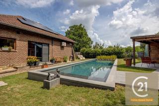 Droomt u van rust, ruimte en natuur, en dat op slechts een steenworp van alle voorzieningen? Dan is deze charmante villa op 2 percelen van samen 2.523 m² precies wat u zoekt. Deze prachtige woning is omgeven door groen en biedt volledige privacy dankzij de bomen rondom het domein — het voelt als een privébos waar u in alle stilte kunt wandelen en genieten van de natuur in uw eigen achtertuin.<br /><br />De woning beschikt over een prachtig zwemvijver met een stijlvolle loungehoek, perfect om te ontspannen of gasten te ontvangen bij een zomerse barbecue. Aansluitend aan de woning bevindt zich een ruime veranda met een panoramisch zicht op de uitgestrekte, perfect onderhouden tuin. Halverwege het perceel vindt u drie garages, ideaal voor het opbergen van tuinmateriaal of extra opslag.<br /><br />De villa biedt naast deze buitenpracht ook comfort en functionaliteit binnenin. Er zijn drie slaapkamers, waarvan twee op het gelijkvloers en één zeer ruime kamer op de verdieping — deze laatste kan makkelijk worden opgedeeld in twee aparte kamers. De recent gerenoveerde badkamer straalt luxe en moderniteit uit. In de leefruimte en master bedroom is airconditioning voorzien voor extra comfort. Verder is er een kelder, een tuinhuis, een carport aan de zijkant van de woning, én een atelier achter de garage — ideaal voor wie graag klust of creatief bezig is.<br /><br />Ook aan duurzaamheid werd gedacht: op het dak liggen zonnepanelen die bijdragen aan een lagere energiefactuur. Parkeren is geen enkel probleem dankzij de ruime oprit met plaats voor vier wagens en de dubbele inpandige garage.<br /><br />Deze unieke eigendom biedt een zeldzame combinatie van rust, ruimte, comfort en natuurbeleving, vlakbij het centrum van Machelen. Een buitenkans voor wie wil wonen in een oase van groen met alle comfort van een moderne woning.<br /><br />Voor meer info en foto's kijk op www.century21vilvoorde.be