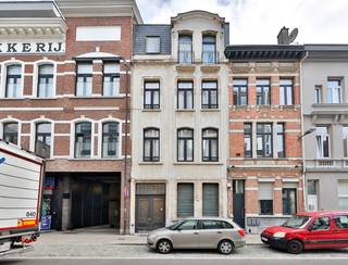 <p>Een stijlvolle <strong>burgerwoning van maar liefst 357 m²</strong>, doordrenkt met authenticiteit, licht en ruimte. En dat allemaal achter die knappe gevel die meteen de toon zet.</p>
<p>Via de prachtige inkomdeur stap je de royale hal in op originele terrazzo vloer, waar het warme houtwerk en de hoge plafonds je welkom heten. Aan de rechterkant bevindt zich een verrassend ruime bureau- of hobbykamer, ideaal voor wie thuis werkt of creatief uit de hoek komt. Achteraan ligt een groot atelier/opslagruimte, perfect voor makers, verzamelaars of professionals die hun werkruimte onder hetzelfde dak willen.</p>
<p>De brede trap brengt je naar de eerste verdieping waar het echte woongedeelte zich ontvouwt.<br />Een lichtrijke leefruimte met hoge plafonds, originele houten vloeren en sfeer in elke hoek.<br />De keuken, modern maar met karakter, brengt licht binnen langs elke kant en sluit heerlijk aan op het terras.</p>
<p>De tweede verdieping herbergt 2 royale slaapkamers en een stijlvolle badkamer met een ruim ligbad, dubbele lavabo, zachte kleuren en een rustgevende sfeer. De perfecte ruimte om je dag te starten of af te sluiten! Minder ontspannend maar wel o-zo-handig is de berging voor wasmachine en droogruimte, perfect geïntegreerd in de badkamer. En alsof het niet op kan, is hier aanpalend nog een extra terras (<em>niet vergund)</em>.</p>
<p>En dan, bovenaan: een volledig afgewerkte <strong>studio</strong> met eigen leefruimte, keuken en badkamer. Perfect voor een inwonende student, een au-pair, een extra bron van inkomsten of gewoon je eigen creatieve cocon.</p>
<p>Doorheen de woning zie je hoe zorgvuldig alles werd gerenoveerd in 2004: originele elementen behouden, karakter gerespecteerd, maar toch klaar voor vandaag.</p>
<p><strong>Troeven in één oogopslag:<br /></strong>- Prachtige burgerwoning met uitstraling<br />- Groot atelier/opslag op het gelijkvloers<br />- Woning + aparte studio voor gasten, werk of verhuur<br />- Volledig gerenoveerd (2004) met kwalitatieve materialen en behoud van originele elementen<br />- Royale leefruimtes en veel natuurlijk licht<br />- Ideaal voor wonen + werken of co-house<br />- Ruim, origineel, karaktervol<br /><br />Kom je dit knappe geheel zelf ontdekken? Plan een afspraak in, we tonen het met plezier.<br /><br />Wg, Gvkr, Gvv, Gmo, Geen overstromingsgevoelig gebied</p>