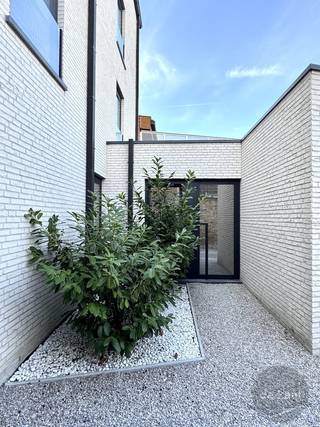 Beleef het huisgevoel in een appartement! <br />Achterliggende woning in de nieuwbouwresidentie Lombard'sea, met afzonderlijke ingang en tuin. <br />Geniet hier in alle rust alle comfort! <br />Knappe woning met mooie inkomhal, gezellige woonkamer uitgevend op het terras en de tuin. <br />Goed ingerichte keuken voorzien van alle comfort en toestellen. Aansluitend een praktische bergplaats met aansluiting voor wasmachine. <br />Twee volwaardige kamers waarvan 1 volledig ingericht is met ingebouwde kasten. <br />Badkamer met inloopdouche en lavabomeubel. Afzonderlijk toilet. <br />Bergplaats en fietsenberging. Garagebox achteraan het gebouw inbegrepen in de prijs. <br /><br />