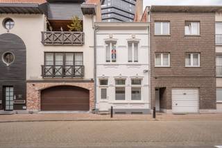Gelegen in het hart van Heist-aan-Zee, nabij het Heldenplein, het strand en de kusttram, vindt u deze unieke woning uit 1954. Een zeldzame, karaktervolle en authentiek gerenoveerde woning met oog voor detail: prachtige gevel, originele trappenhal en houten vloeren.<br /><br />De woning beschikt over 4 slaapkamers (18, 18, 15 en 13 m² – samen 64 m²), een lichtrijke eetplaats en living (32 m²) met openende raampartijen, en een stijlvolle keuken (FRAKO) met stenen werkblad en SMEG-toestellen.<br /><br />Er zijn 2 badkamers (waarvan één en-suite), lavabo’s op de kamers, en een toilet op elke verdieping. Daarnaast is de woning volledig onderkelderd (26 m²) met wasplaats en bergruimte.<br />Buiten geniet u van een aangenaam terras (12 m²) en een aparte buitenberging.<br /><br />Instapklaar en onmiddellijk beschikbaar.<br />Optioneel: garagebox aan de overzijde.