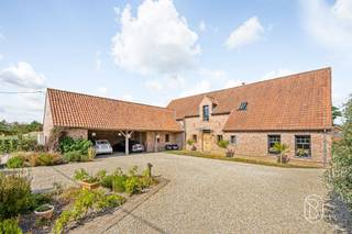 Luxueuze villa met paardenaccomodatie, in een groene, landelijke omgeving. Op een prachtige rustige locatie bevindt zich deze uitzonderlijke villa, opgetrokken in een stijlvolle landelijke architectuur en afgewerkt met hoogwaardige materialen. Deze eigendom combineert charme, comfort en kwaliteit en biedt een unieke woonbeleving voor wie houdt van ruimte, rust en een verfijnde levensstijl.Bij het betreden van de woning valt meteen de aandacht voor detail op. De natuurstenen vloeren, keukenbladen in hoogwaardige materialen en het volledig uitgevoerde binnenschrijnwerk in volle eik getuigen van een tijdloze elegantie. Het buitenschrijnwerk in tropisch hardhout onderstreept de duurzame en kwalitatieve afwerking van deze prachtige villa.De woning beschikt over ruime en lichtrijke leefruimtes, ideaal voor zowel dagelijks comfort als het ontvangen van gasten. Met 5 slaapkamers en 2 badkamers biedt de villa alle ruimte voor een gezin of wie extra kamers wenst voor kantoor, hobby of logies. Op het gelijkvloers bevindt zich een bijzonder comfortabele mastersuite met dressing en aansluitende badkamer.Buiten geniet u van een prachtig aangelegde tuin met sfeervolle waterpartij, die naadloos aansluit op de omliggende weide. De aanwezigheid van paarden- of ponystallingen maakt deze eigendom bijzonder aantrekkelijk voor paardenliefhebbers of wie droomt van een landelijke levensstijl.Daarnaast beschikt de woning over een ruime carport voor 3 wagens en tal van praktische voorzieningen.Een uitzonderlijke eigendom, perfect onderhouden tot in de kleinste details, waar kwaliteit, ruimte en landelijke charme harmonieus samenkomen.