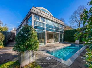 <p><strong>Riante en moderne villa in de gegeerde Elsdonckwijk – Wilrijk</strong></p>
<p>Deze prachtige villa combineert ruimte, comfort en luxe in een van de meest prestigieuze villawijken van Wilrijk. Gelegen in een rustige straat, op korte afstand van openbaar vervoer, supermarkten, restaurants en belangrijke in- en uitvalswegen, geniet u hier van optimale bereikbaarheid én privacy.</p>
<p><strong>INDELING</strong></p>
<p><strong>Gelijkvloerse verdieping:</strong><br />De ruime inkomhal verwelkomt u en leidt naar de lichtrijke living met eetruimte en zitruimte. De volledig ingerichte keuken is verbonden met de eetkamer via een brede schuifdeur, wat een open, vloeiende indeling creëert en tegelijk de mogelijkheid biedt tot afzonderlijke ruimtes. De keuken is uitgerust met een 5-pits gasvuur, hete luchtoven, afwasmachine en grote Amerikaanse koelkast en loopt naadloos over in de praktische bijkeuken met ingemaakte kasten. Zowel de keuken als de living genieten van grote raampartijen met toegang tot het terras en de zonnige tuin.<br /><br />Onder het terras bevindt zich een voormalig zwembad dat opnieuw in gebruik kan worden genomen – een unieke troef voor wie droomt van een eigen zwembad.</p>
<p>Daarnaast is er een volledig ingerichte suite met slaapkamer, badkamer met bad, douche, dubbele wastafel, wc en dressingruimte. Deze is ideaal te gebruiken als gastenverblijf of thuiskantoor, wat extra flexibiliteit biedt voor gezinnen of thuiswerkers.</p>
<p>De garage biedt plaats aan één wagen en meerdere fietsen.</p>
<p><strong>Eerste verdieping:</strong><br />Via een gepantserde deur bereikt u de nachthal met toegang tot 5 ruime slaapkamers (ca. 14 m², 15 m², 19 m², 17 m² en 23 m²). Slaapkamers 1 en 2 delen een badkamer met dubbele wastafel, bad met douchefunctie en aparte wc. Slaapkamers 3 en 4 beschikken elk over een en suite badkamer met dubbele wastafel en bad met douchefunctie. De masterbedroom (ca. 23 m²) is voorzien van ingemaakte kasten en een en suite badkamer met ligbad, dubbele wastafel, douche en wc en en baadt dankzij de grote raampartij in natuurlijk licht.</p>
<p><strong>Tweede verdieping:</strong><br />De recent gerenoveerde zolderverdieping is omgevormd tot een zelfstandig appartement met nachthal en ingemaakte kasten, badkamer met ruime inloopdouche, dubbele wastafel en toilet, een slaapkamer en een grote polyvalente ruimte van ca. 30 m². <br />Deze ingerichte zolder is bijzonder geschikt indien de woning als kangoeroewoning wordt gebruikt, waardoor wonen met meerdere generaties of een combinatie van privé en werkruimte eenvoudig mogelijk is.</p>
<p><strong>BIJZONDERHEDEN</strong></p>
<ul>
<li>Ruime en moderne villa met hoogwaardige afwerking</li>
<li>Prestigeuze locatie in de Elsdonckwijk</li>
<li>Oprit voor meerdere wagens en garage aanwezig</li>
<li>Kelder aanwezig</li>
<li>Gunstige EPC: B</li>
<li>Slaapkamer op gelijkvloers, flexibel te gebruiken als gastenverblijf of thuiskantoor</li>
<li>Vroegere zwembad onder het terras, die terug kan opengekapt worden</li>
<li>Mogelijkheid tot kangoeroewoning</li>
</ul>
<p><strong>Kortom:</strong> een unieke villa die luxe, ruimte en flexibiliteit perfect combineert voor een groot gezin of wie wonen en werken thuis wil combineren.</p>
<p>Voor meer informatie of een bezoek aan deze prachtige woning neem gerust contact op met Sigalit via Sigalit@reds.be of via 0475 66 84 74</p>