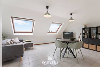 Voor meer info en foto’s, surf naar www.swevers.be – Op de derde verdieping van een verzorgd gebouw aan de Vredelaan 43 bus 3.01 in Houthalen-Helchteren ligt dit praktisch ingedeelde 1-slaapkamerappartement. Het gebouw dateert van 1988 en heeft een bewoonbare oppervlakte van 65m2. Dankzij de centrale ligging bevinden winkels en openbaar vervoer zich op amper 50 meter. Ook scholen, ontspanning, restaurants en belangrijke verbindingswegen zijn vlot bereikbaar. Ideaal voor eigen bewoning of als investering met het oog op verhuur. Het appartement beschikt over een lichtrijke leefruimte van 26,88 m² met grote raampartijen en dakramen. De open keuken van 4,70 m² sluit hier rechtstreeks op aan en werd in 2019 vernieuwd. Er is voldoende ruimte voor een gezellige zit- en eethoek. De ruime slaapkamer van 16,40 m² biedt plaats aan een dubbel bed en extra kastruimte. De badkamer is uitgerust met een douche, wastafelmeubel en toilet. Het badkamermeubel en toilet werden in 2019 vernieuwd en in 2024 kwam er een nieuwe spiegelkast bij. Doorheen de jaren werd het appartement gericht opgefrist. Zo werd in 2008 het Velux-dakraam in de badkamer vernieuwd en voorzien van een PVC-afwerking en dubbele beglazing en werden in 2019 onder meer de keuken en boiler vernieuwd. De elektriciteit is conform. Er is geen terras, maar de natuurlijke lichtinval, onderhoudsvriendelijke indeling en centrale ligging vormen duidelijke troeven. Een interessant appartement voor wie comfortabel en centraal wil wonen of op zoek is naar een vlot verhuurbare investering in Houthalen-Helchteren. Voor meer informatie, bel 011 255 155. Bron bewoonbare oppervlakte: EPC – verslag.