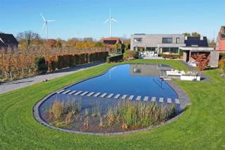<p><span>Via de inkomhal, met een ruime berging en gastentoilet, betreedt u de leefruimte. Deze bestaat uit een open en lichtrijke living/zithoek met gashaard, een eetgedeelte en een volledig ingerichte open leefkeuken. De keuken is uitgerust met een kookeiland, dubbele lavabo, oven en stoomoven, twee warmhoudlades, een teppanyaki-plaat en een wijnfrigo, alle toestellen van Miele.</span></p><p><span> </span></p><p><span>Op de eerste verdieping bevindt zich de masterbedroom met ensuite badkamer, voorzien van een dubbele inloopdouche, dubbele wastafel en een aparte dressing met inbouwkasten. Daarnaast zijn er nog twee slaapkamers, elk uitgerust met ingebouwde kasten, een apart toilet en een badkamer met ligbad en inloopdouche.</span></p><p><span> </span></p><p><span>De woning is volledig onderkelderd en voorzien van een aparte wasplaats, een grote polyvalente ruimte, een aparte wijnkelder en een dubbele inpandige garage. </span></p><p><span> </span></p><p><span>Er werd gebruikgemaakt van hoogwaardige materialen zoals (moeras)eik, (cappuccino)marmer en natuursteen. Alles is ontworpen met aandacht voor comfort, wat resulteert in een hedendaagse en ruime villa met grote raampartijen die zorgen voor een overvloed aan licht en prachtige zichten op de tuin.</span></p><p><span> </span></p><p><span>Vanuit de volledige woning geniet u van een weids uitzicht op de zuidgerichte tuin en de achterliggende velden. De tuin is volledig omheind en voorzien van een zwemvijver. Verder zijn er een tuinberging en een poolhouse met westgericht overdekt terras, uitgerust met douche- en toiletvoorziening.</span></p><p><span> </span></p><p><span>Extra’s: hoge plafonds, vloerverwarming, gashaard, overal zonnewering (elektrische in living en master), dimlichten, alarm, aparte gekoelde wijnkelder, aluminium ramen, parlofoon, automatische poort, regenwaterput van 10.000 liter, zwemvijver, …</span></p><p><span> </span></p><p><span> </span></p><p><span> </span></p><p><span> </span></p>