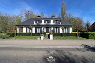 Deze karaktervolle woning is ruim ingedeeld en biedt bovendien de mogelijkheid om volledig gelijkvloers te kunnen wonen. <br />De verdieping beschikt over drie slaapkamers maar de grote zolderruimtes hebben nog veel uitbreidingsmogelijkheden. In de kelder is een grote garage en nog voldoende extra bergruimte. <br />De zichtlocatie is ideaal voor de ondernemer die op het gelijkvloers een kantoor/praktijk zou willen beginnen. De tuin naast de woning is gelegen in woongebied en zorgt nog voor extra potentieel. <br />De fijne, gezellige dorpskern met winkels, bakker en ontspanning ligt op wandelafstand. <br /><br />=> Gelijkvloers<br />- Royale inkomhal met dubbele deuren naar de leefruimte<br />- Deze hal is verrassend luchtig en heeft een apart gedeelte voor vestiaire met gastentoilet<br />- L-vormige woonkamer met prachtige parketvloer en open haard<br />- Het grote schuifraam aan de zijkant zorgt voor direct tuincontact en rechtstreekse toegang tot het groot overdekt terras<br />- Verzorgde en zeer degelijke keuken voorzien van alle gemak<br />- Rechtstreeks toegang naar de tuin en het terras vanuit de keuken <br />- Aansluitend is er een praktische en ruime bijkeuken met uitgietbak <br />- Grote slaapkamer aan de voorzijde van de woning toegankelijk vanuit de badkamer<br />- Betegelde badkamer met ligbad, dubbele wastafel in mooi badkamermeubel en apart af te sluiten toilet<br />- Naast de badkamer is er een aparte betegelde douchecel aanwezig <br /><br />=> Verdieping<br />- Ruime overloop met toegang tot de diverse slaapkamers en apart groot toilet met wastafel<br />- Er zijn drie mooie slaapkamers met vloerbekleding en allen voorzien van een eventuele aansluiting voor eigen wastafel op de kamer<br /><br />=> Zolder en kelder<br />- De grote zolderruimtes aan de zijkanten van de woning bieden nog voldoende uitbreidingsmogelijkheden indien gewenst<br />- De woning is deels onderkelderd met een toffe wijnkelder, bergruimtes en een grote garage <br /><br />=> Tuin<br />- De tuin bij deze woning situeert zich voornamelijk aan de zijkant van het huis en is fijn georiënteerd op het westen <br />- Dit perceel ligt volledig in woongebied hetgeen zorgt voor extra potentieel <br />- U kan via de oprit aan de zijkant van de woning de ondergrondse garage bereiken<br /><br />=> Indeling<br />- Gelijkvloers: inkomhal, aparte vestiaireruimte met gastentoilet, L-vormige woonkamer, keuken, bijkeuken/wasplaats, berging, aparte douchecel, badkamer met apart toilet, grote slaapkamer<br />- Verdieping: ruime overloop, drie slaapkamers, grote toiletruimte met wastafel, grote in te richten zolderruimtes<br />- Kelder: grote inpandige garage, wijnkelder, voorraadkelder, berging, kruipruimte